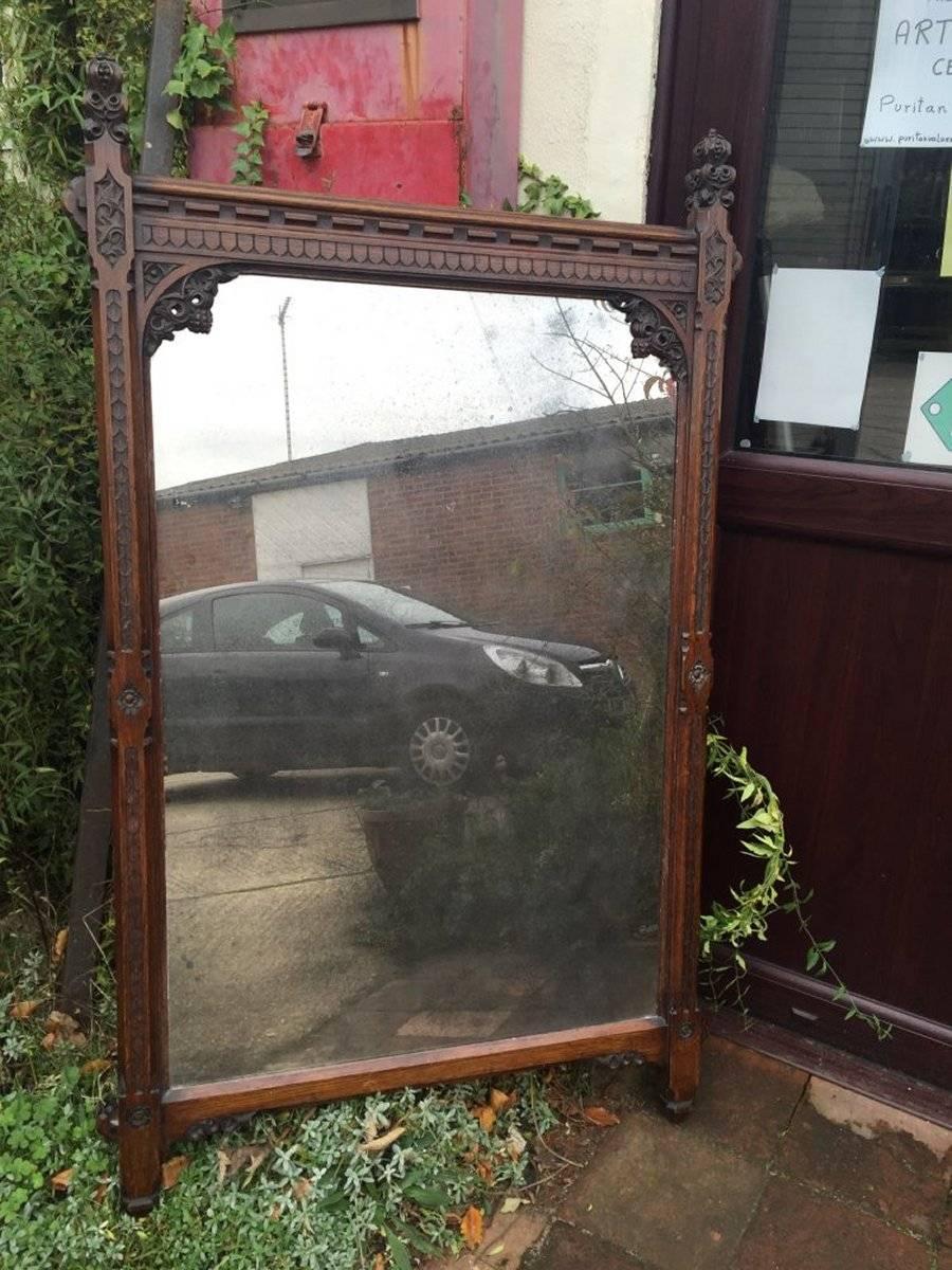 A W N Pugin attributed, A Gothic Revival carved oak wall or pier mirror with a replacement antique style mirror plate.