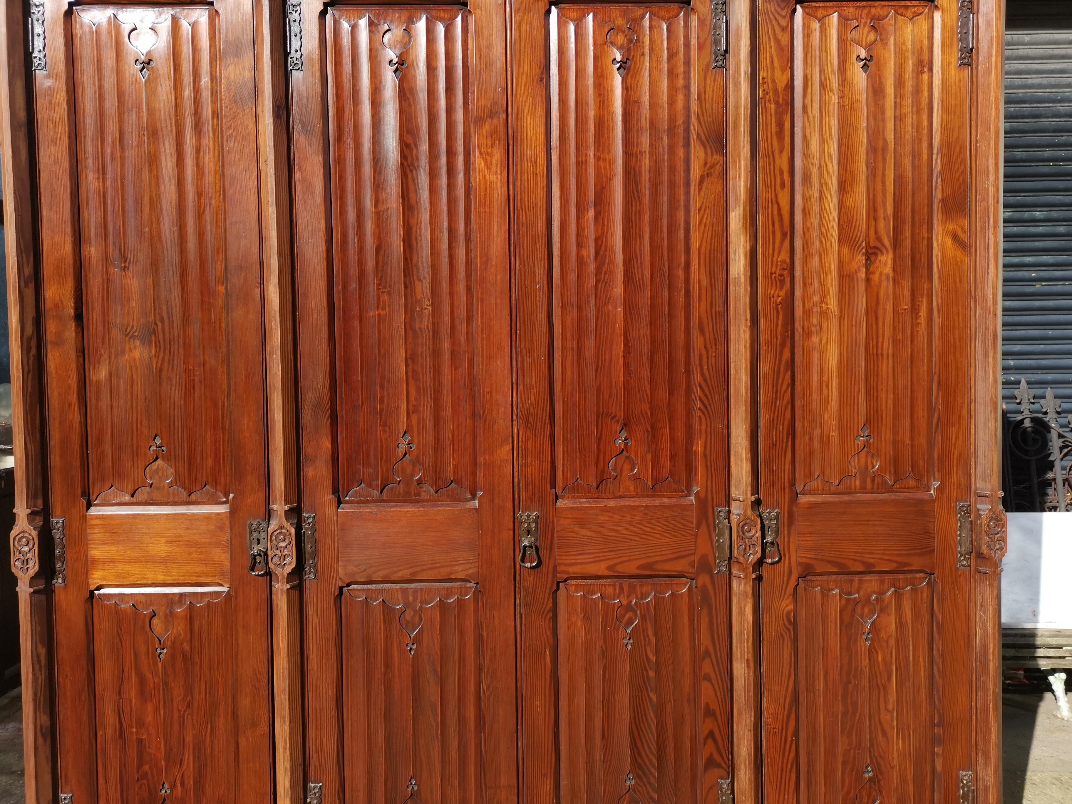 A W N Pugin. Made by John Gregory Crace.
A rare Gothic Revival four-door pitch pine wardrobe with hand-carved fleur de ley finials flanked with castellated hand-carved details to the cornice, and a compilation of four dots below each finial. A