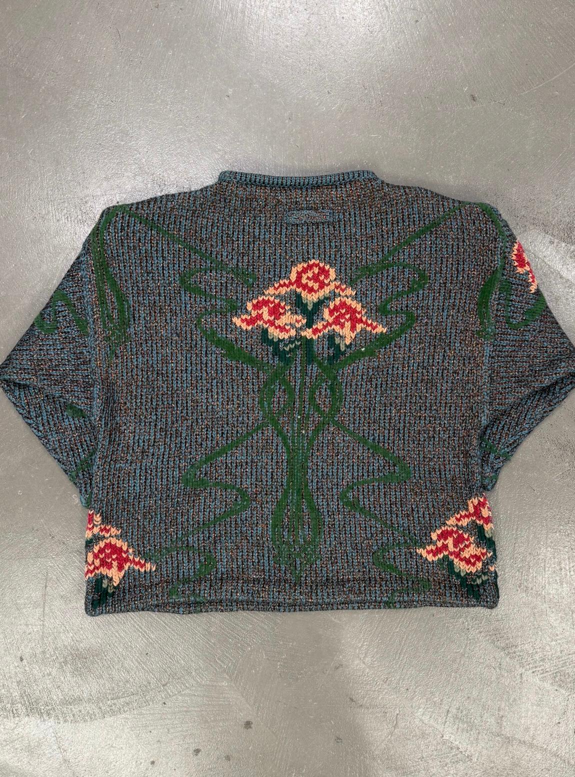 A/W1986 Jean Paul Gaultier - Maille florale en intarsia

Ce rare tricot de Jean Paul Gaultier, issu de la collection Automne/Hiver 1986, présente un motif floral en intarsia dans de riches tons de vert, de rouge et d'ocre. La silhouette cropped boxy