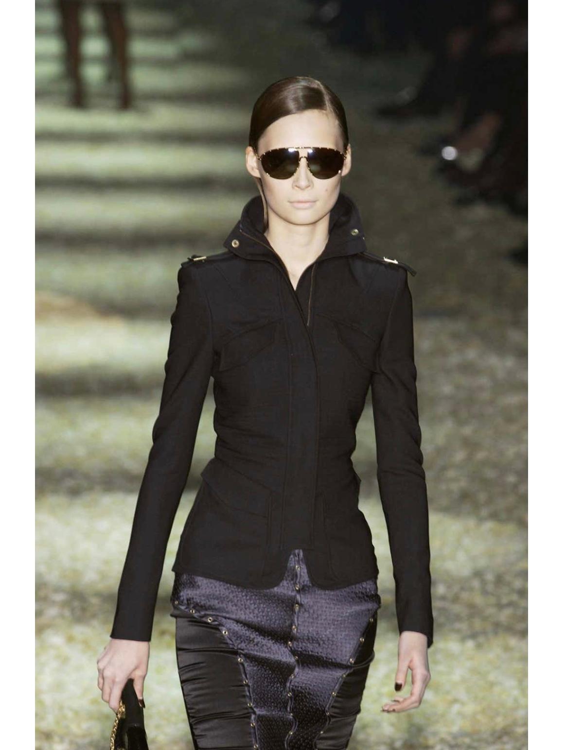 A/W2003 Gucci by Tom Ford veste militaire structurée avec panneaux nervurés matelassés sur la poitrine et les manches, col montant exagéré avec fermeture à glissière dissimulée, et bretelles avec boucles métalliques. Un exemple frappant de la vision