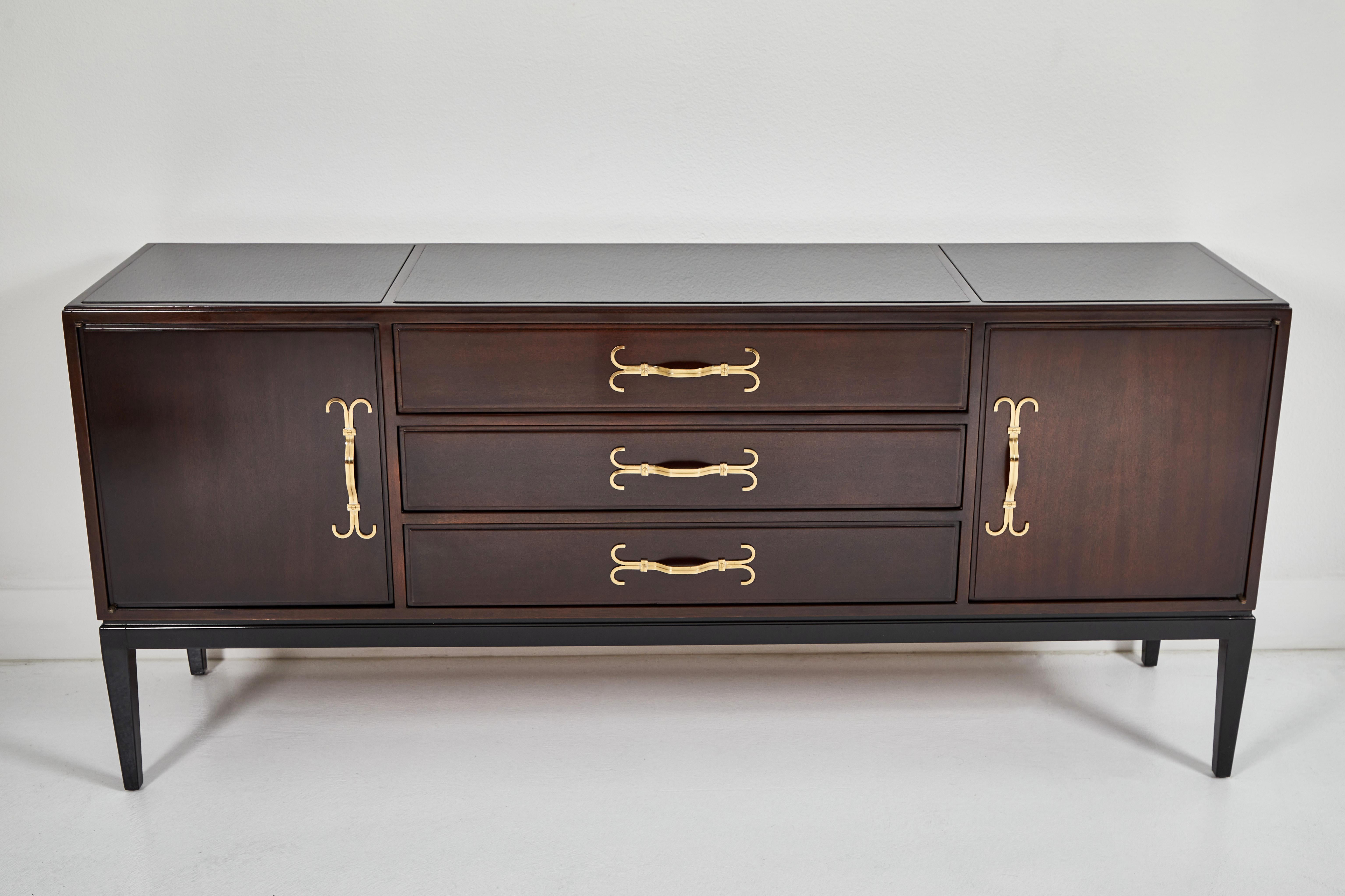 This 1960s original Tommi Parzinger server is in wonderful condition. The walnut is richly stained, yet allows the grain to be visible. The base and legs are black lacquered. The cabinet features two doors and 3 drawers, all with Parzinger’s
