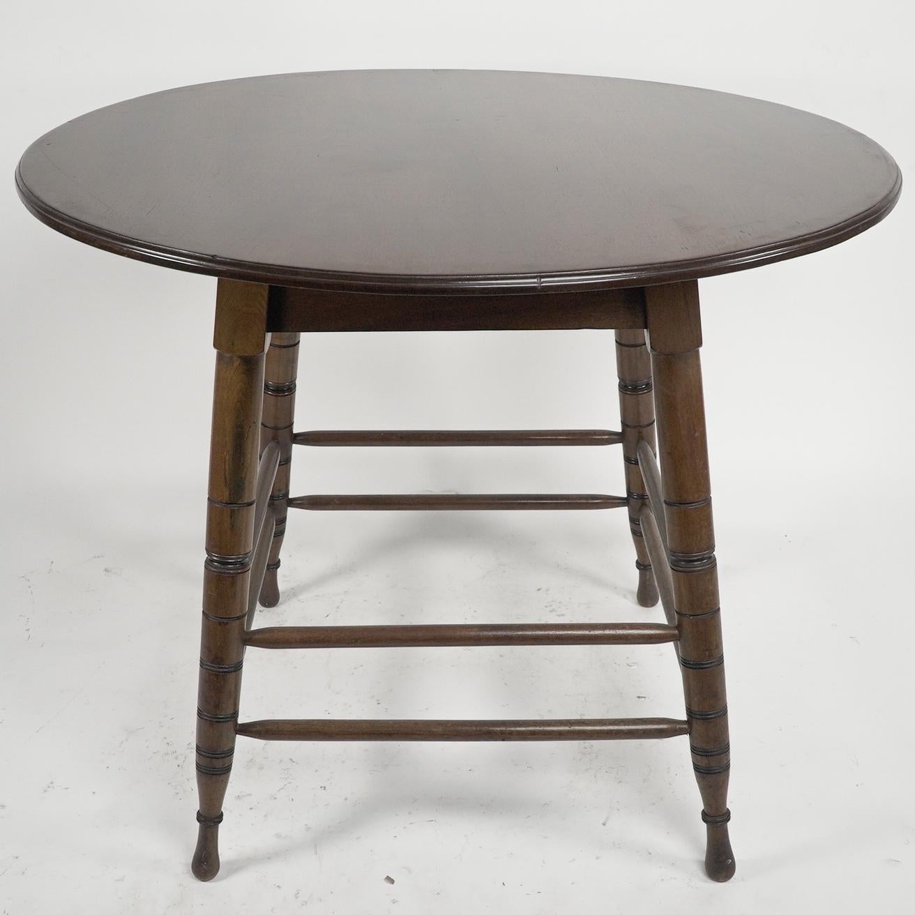 Collinson and Lock, attributed. An Aesthetic Movement Walnut centre table with incised circular details to the legs, united by double cross stretchers.