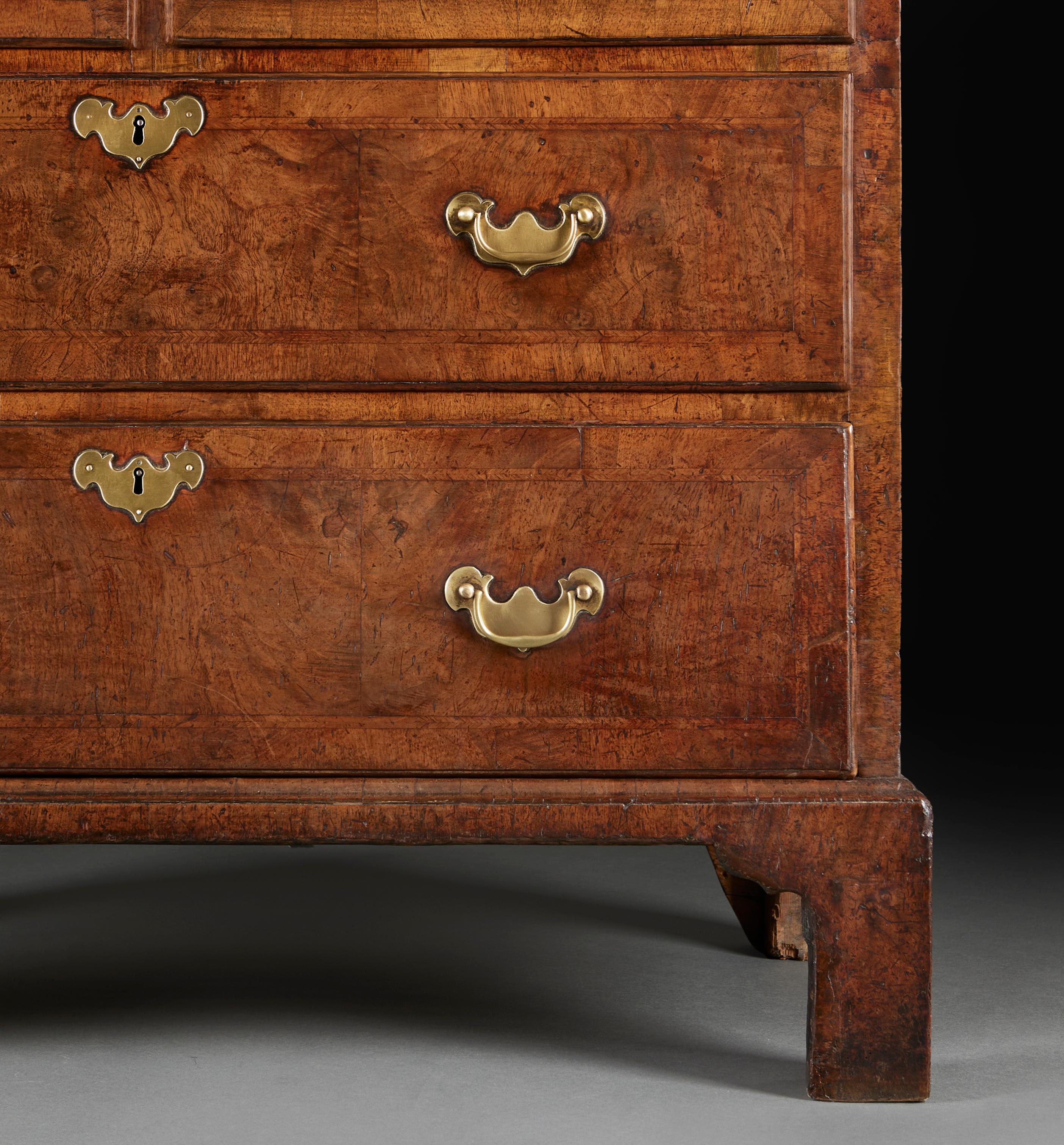 Un raffinato cassettone in noce di Giorgio II, con maniglie e scudi in ottone originali, il piano con cornice concava modanata.