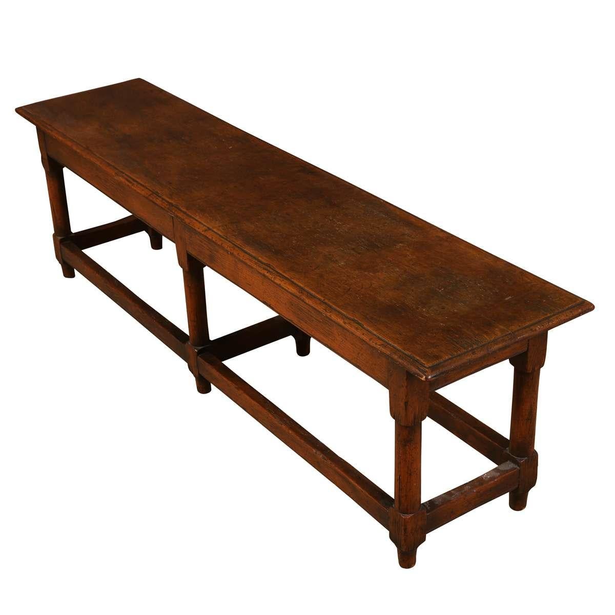 A long oak hall bench inspired by early 17th-century English Jacobean furniture. This reproduction piece features a rectangular plank top, squared legs, and a box stretcher base, reflecting the sturdy construction and rustic charm. Practical use as