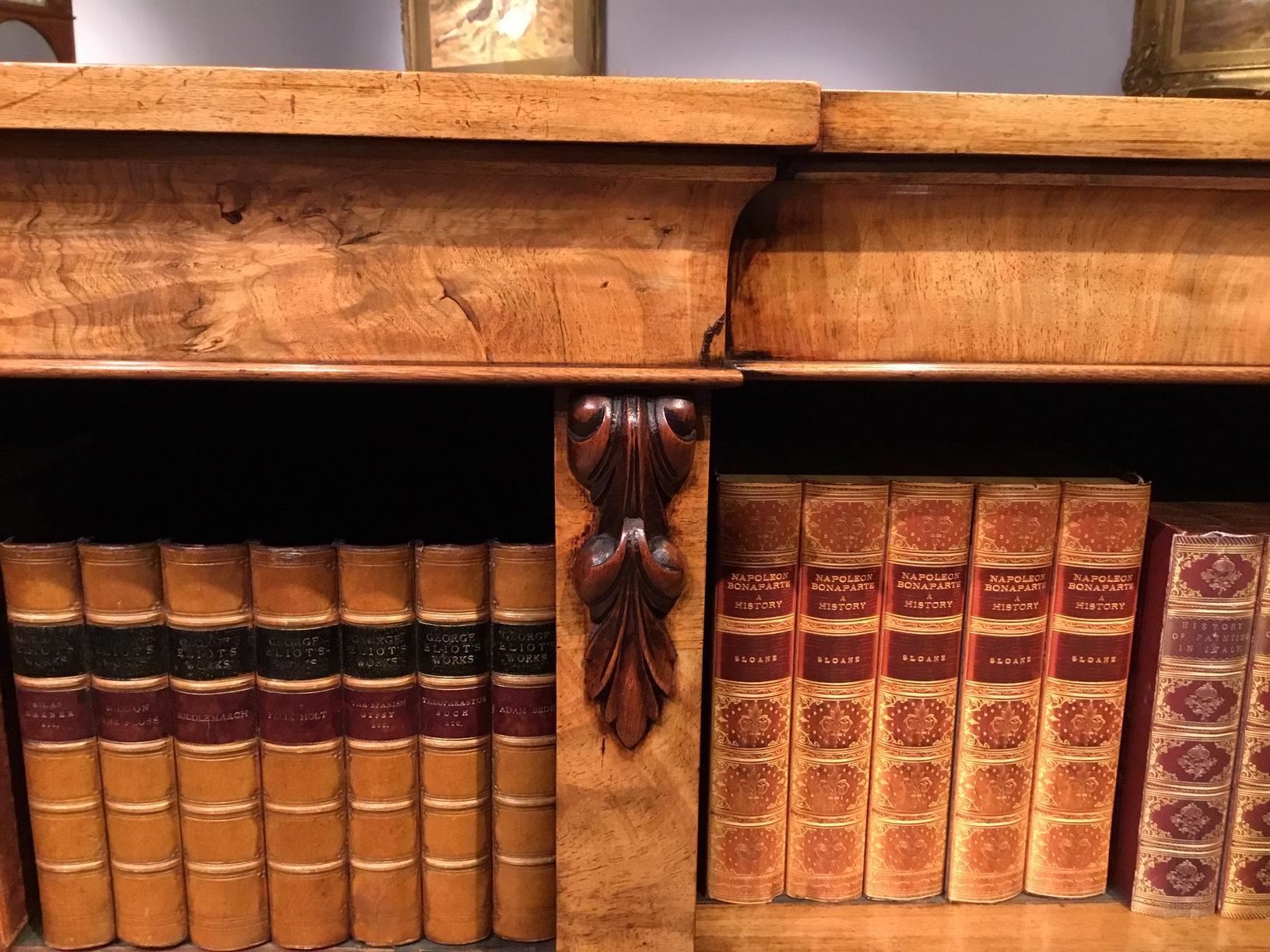 A walnut mid-Victorian period open bookcase. Having a rectangular top of slight breakfront outline and with a cavetto moulded frieze, above an arrangement of nine shelves, six of which are adjustable, with pilasters and finely carved corbels.