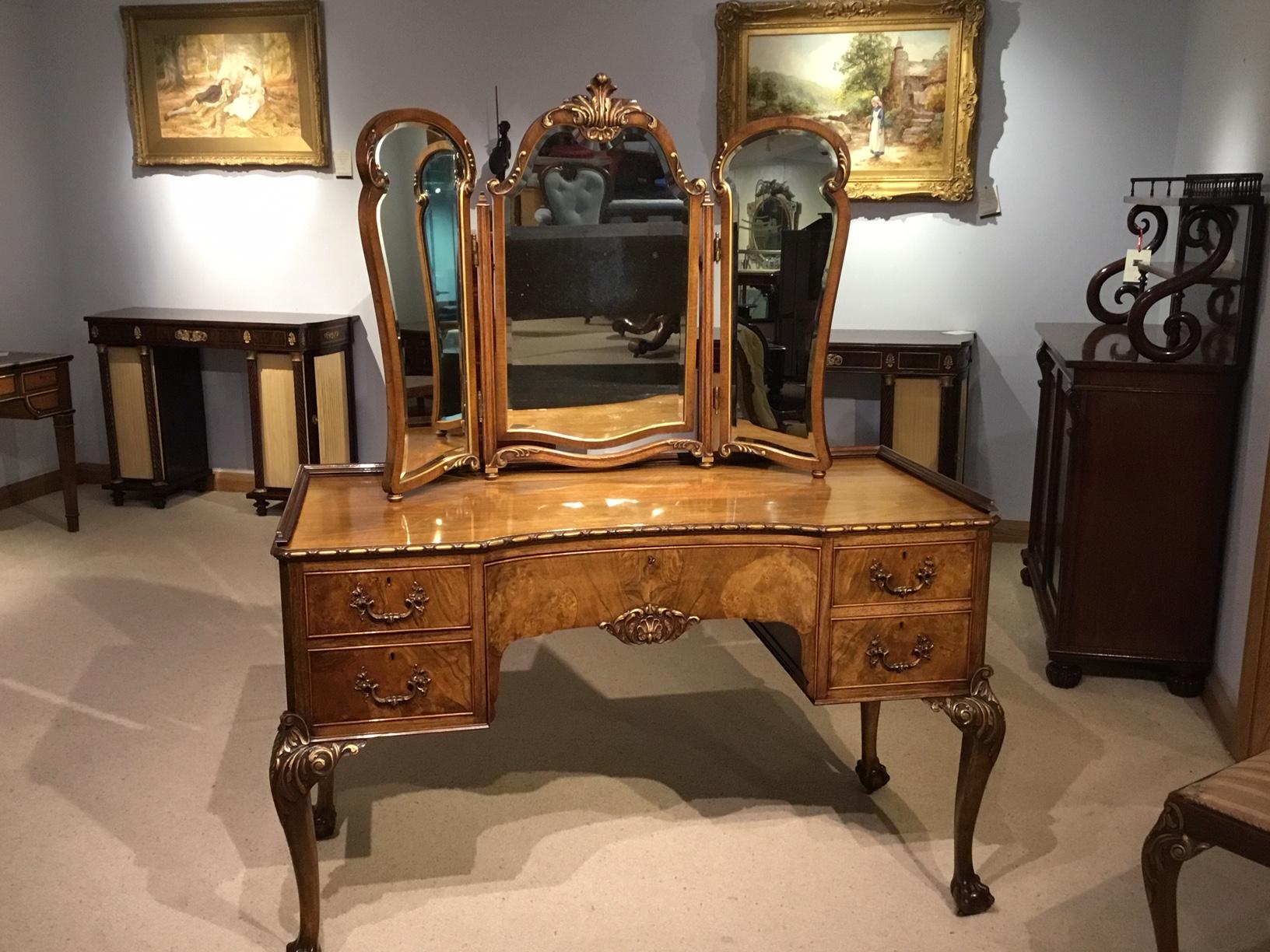 A fine quality walnut and parcel gilt Edwardian period antique dressing table and stool. The removable triptych beveled dressing mirror with fine acanthus and heightened gilt carved detail sitting on a concave shaped base with egg and dart molding.