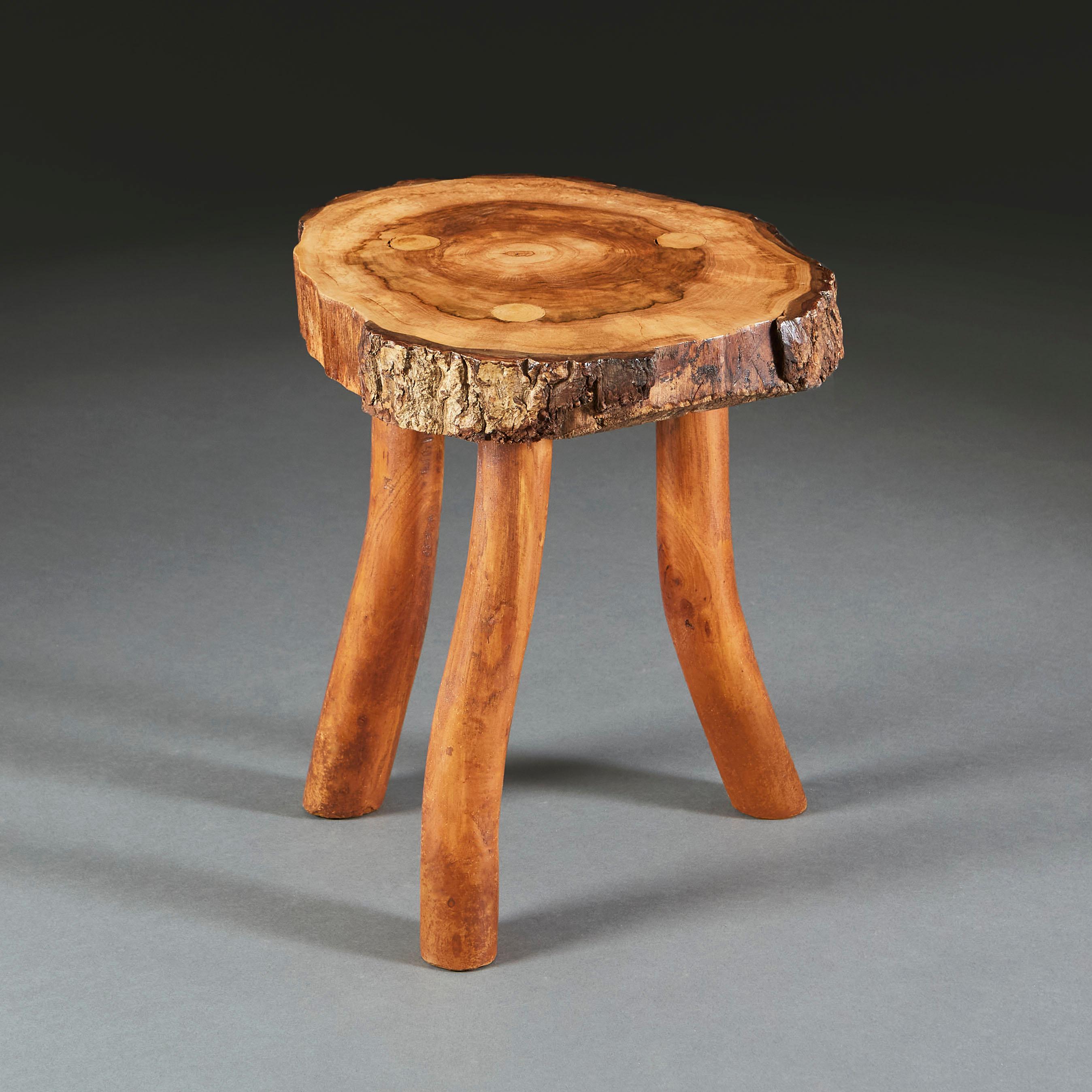 A French walnut root wood tripod table, showing annual growth rings and with natural bark edge.