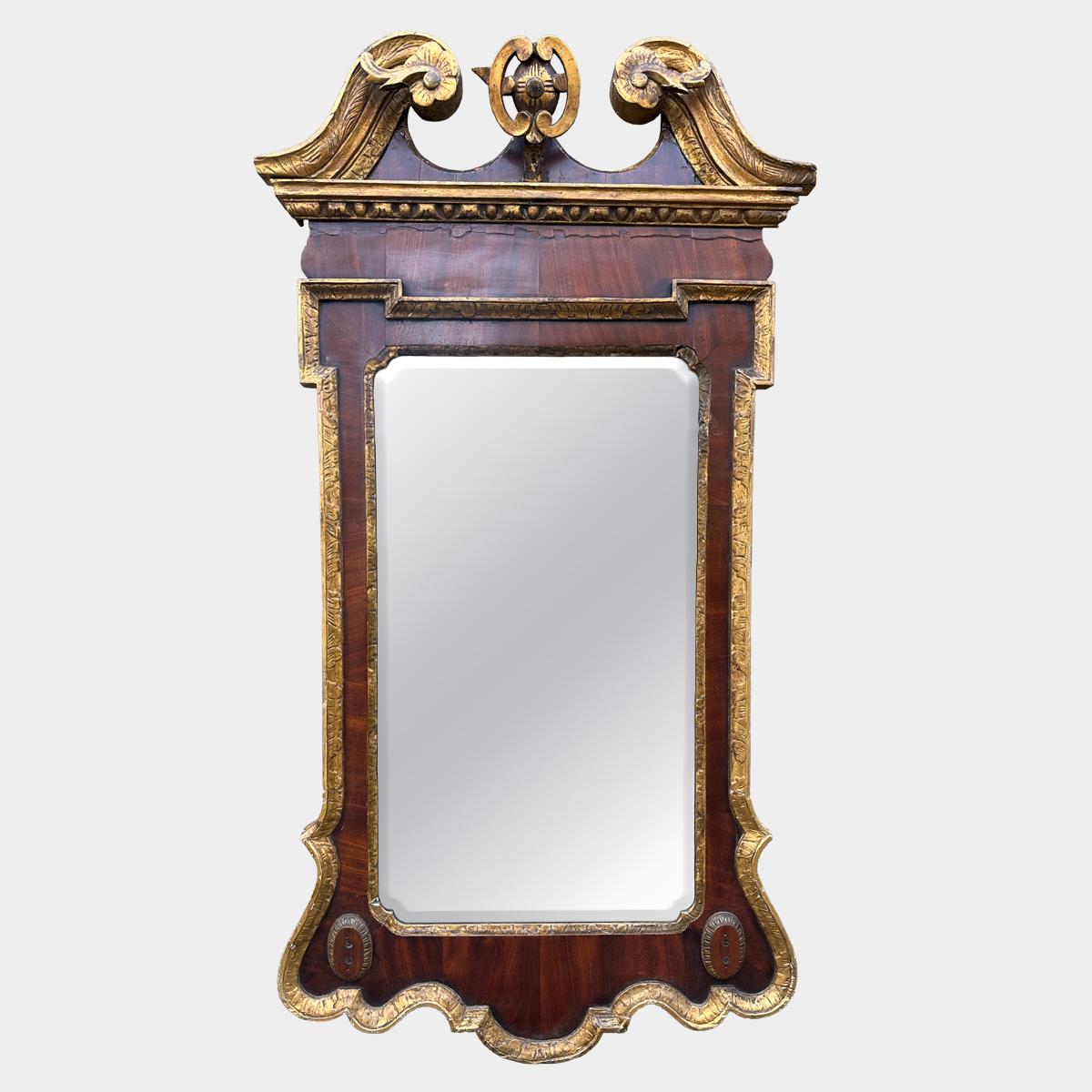 Miroir géorgien en noyer et bois doré. Le sommet à fronton brisé avec des volutes et des rosettes, la bordure extérieure dorée avec le cadre intérieur Kit Kat et le verre biseauté. Une réparation ancienne le long de la partie inférieure du fronton,