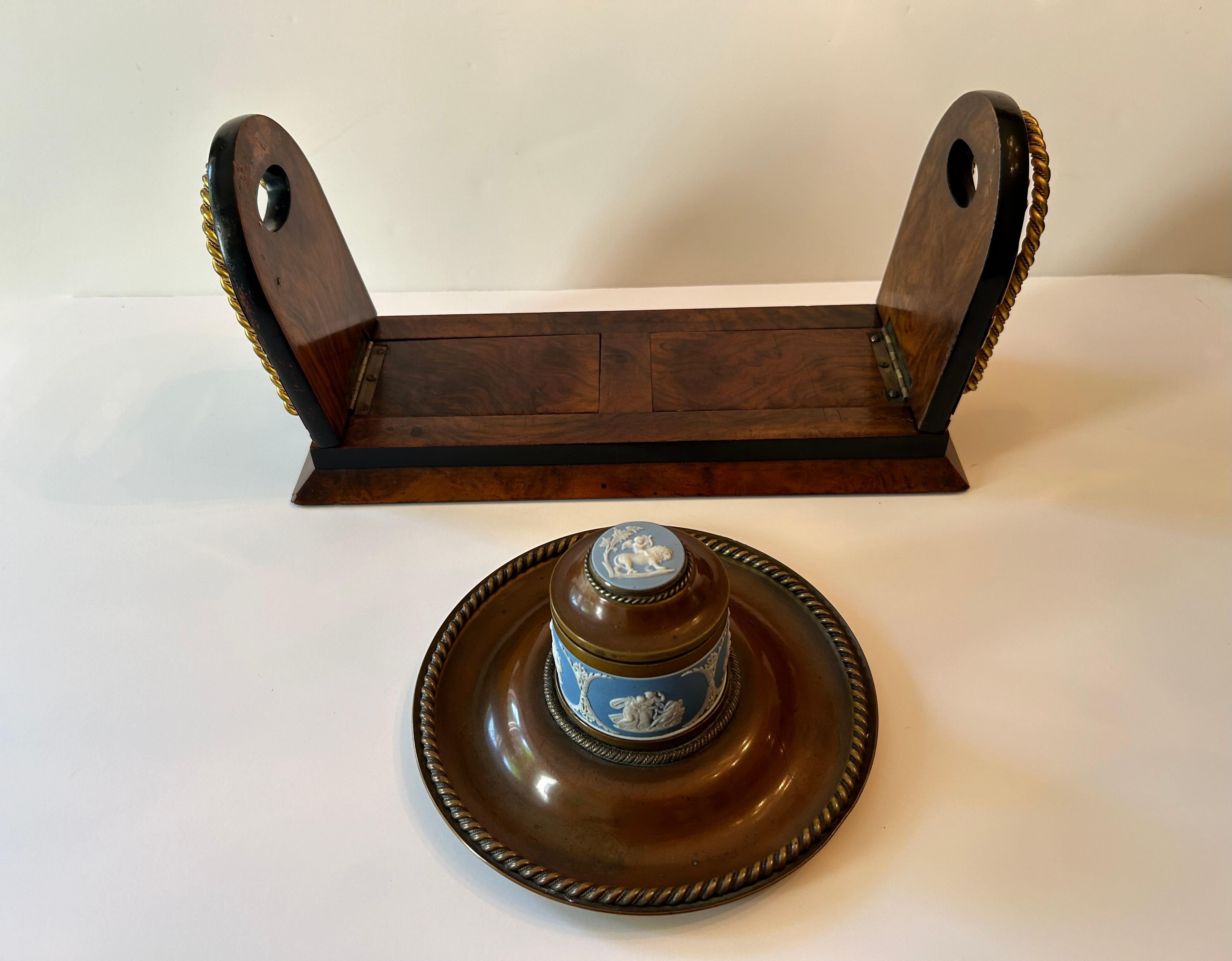 A lovely and very unusual expandable bookshelf, made of burled walnut with brass end plates featuring two Wedgwood Jasperware medallions. The end plates fold down when not in use, and the bookshelf expands easily to accommodate the number of books.