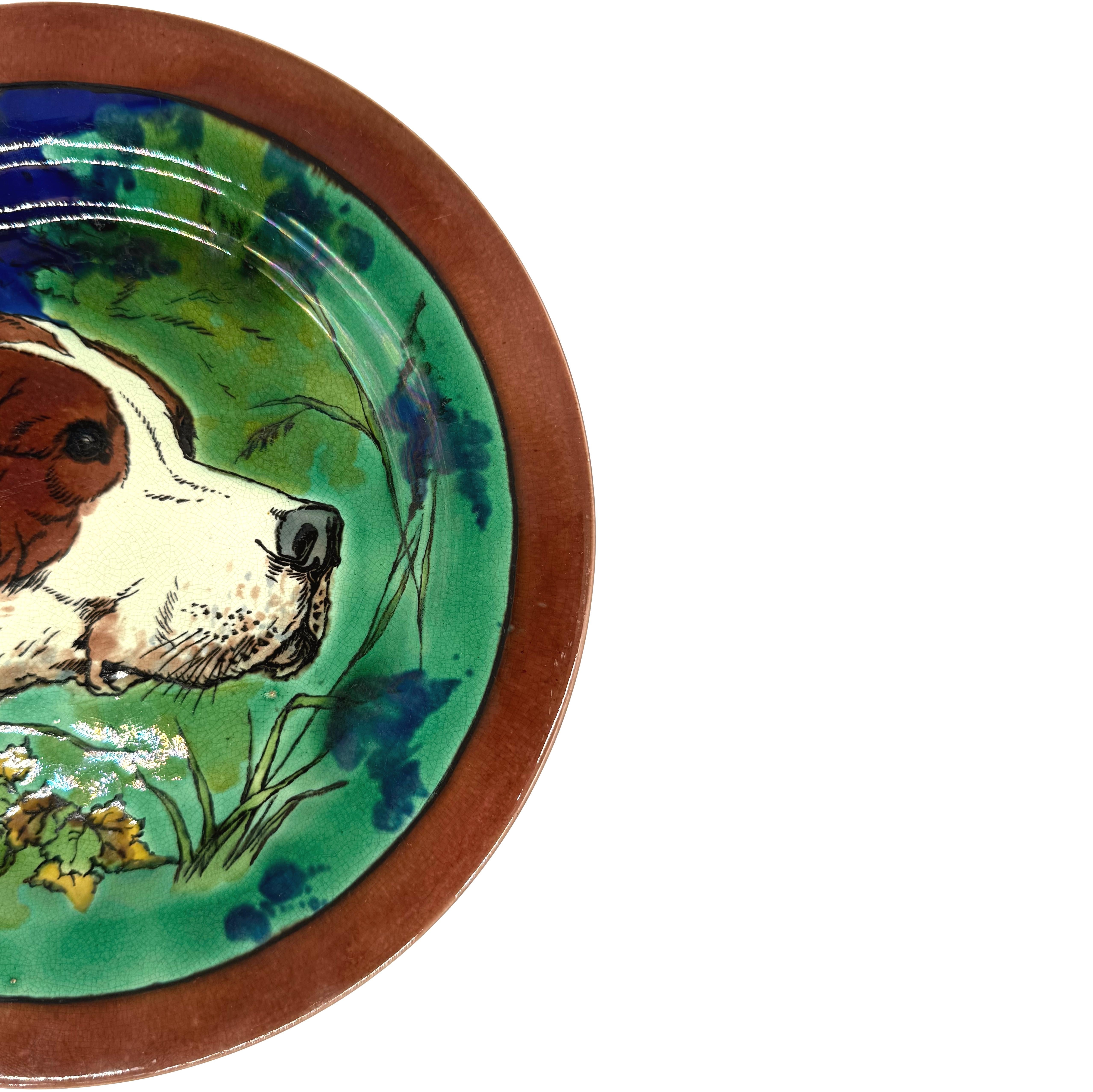 Plato de gabinete de mayólica Wedgwood, inglés, 1877. Diseñado para Wedgwood por el general Henry Hope Crealock (británico, 1831-1891). La escena central representa un perro impreso por transferencia y adornado a mano en un entorno boscoso. El