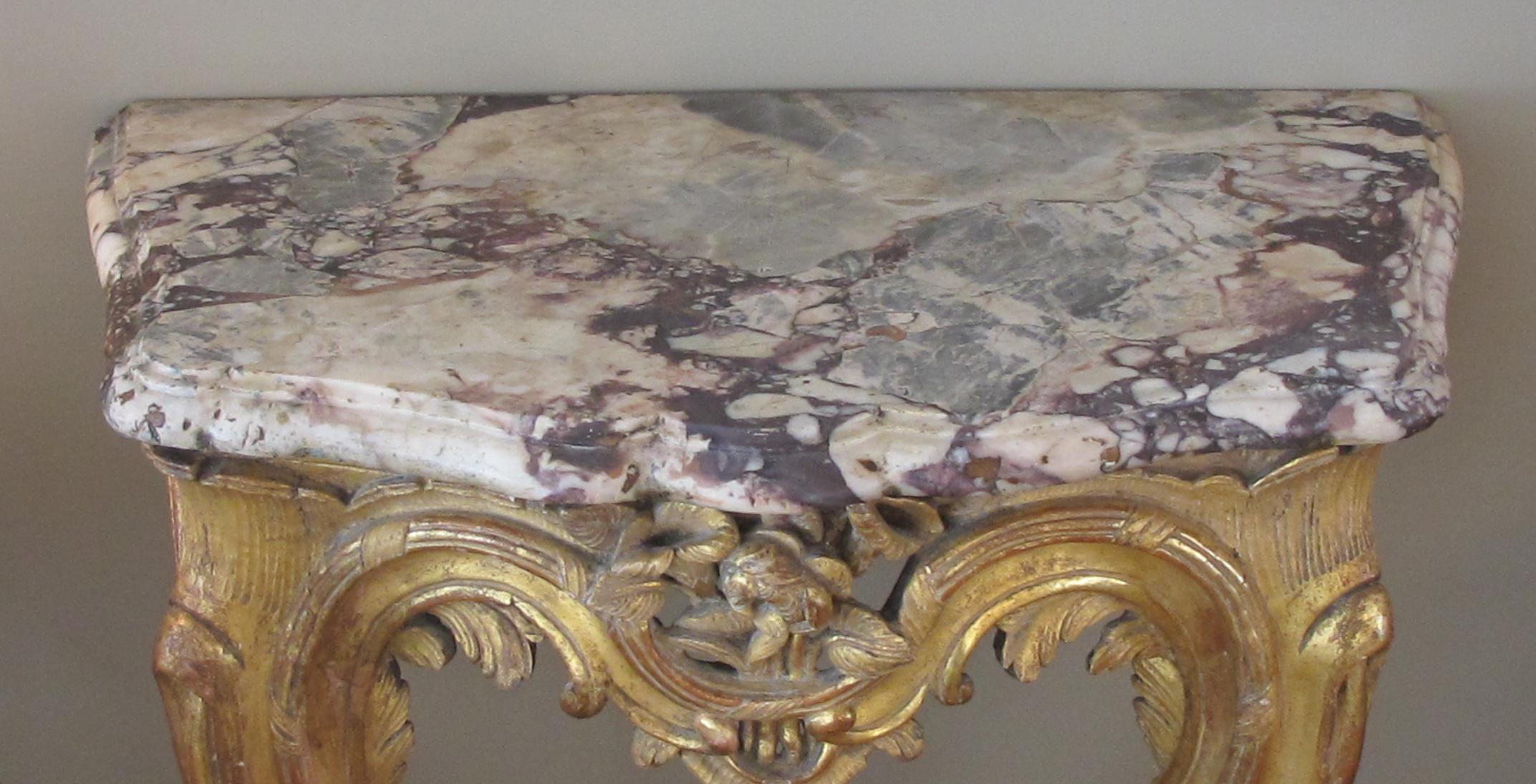 A curvaceous and well-carved Italian Rococo giltwood wall console table with calcutta viola marble top; with original thickly cut, serpentine-form marble top above a conforming console of finely carved floral bouquets and acanthus leaves.