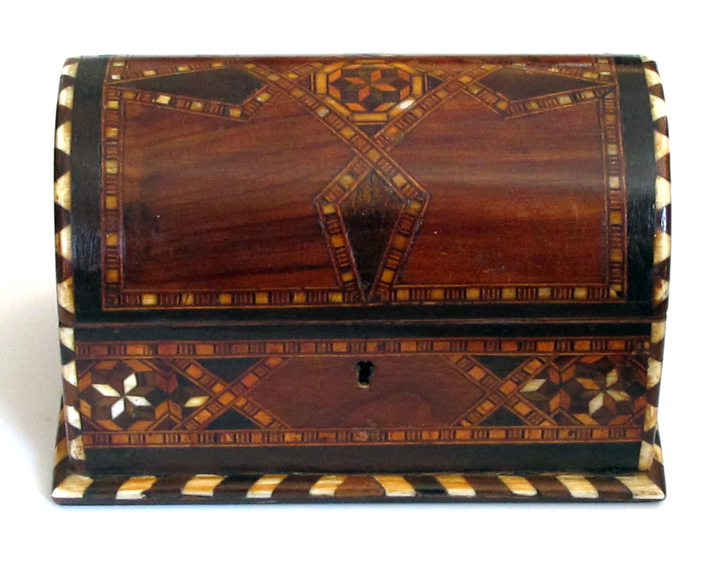 The domed rectangular lid above a conforming body; the whole with fine geometric inlay of exotic woods and bone.