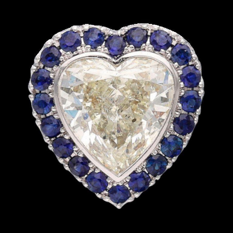 Centering a heart-shaped diamond, accented by round sapphires. 
- Diamond weighs 1.55 carats 
- Sapphires weigh a total of 0.80 carat 
- 18 karat white gold 
- Total weight 2.27 grams 
- Length 1/2 inch,
- Width 1/2 inch