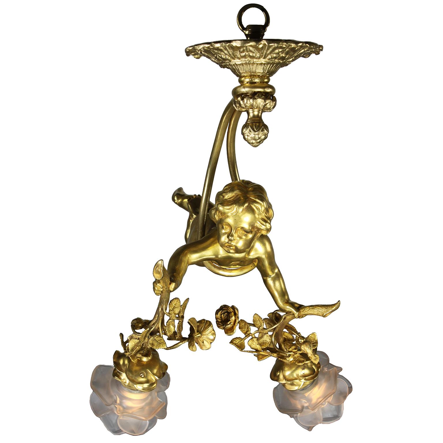 A charming whimsical French 19th/20th century Belle Époque two-light gilt bronze figural chandelier pendant. The charming gilt bronze figure of a naked hovering Putto (Child), suspended from a ribbon-tied tassel wrapped around his body, holding a