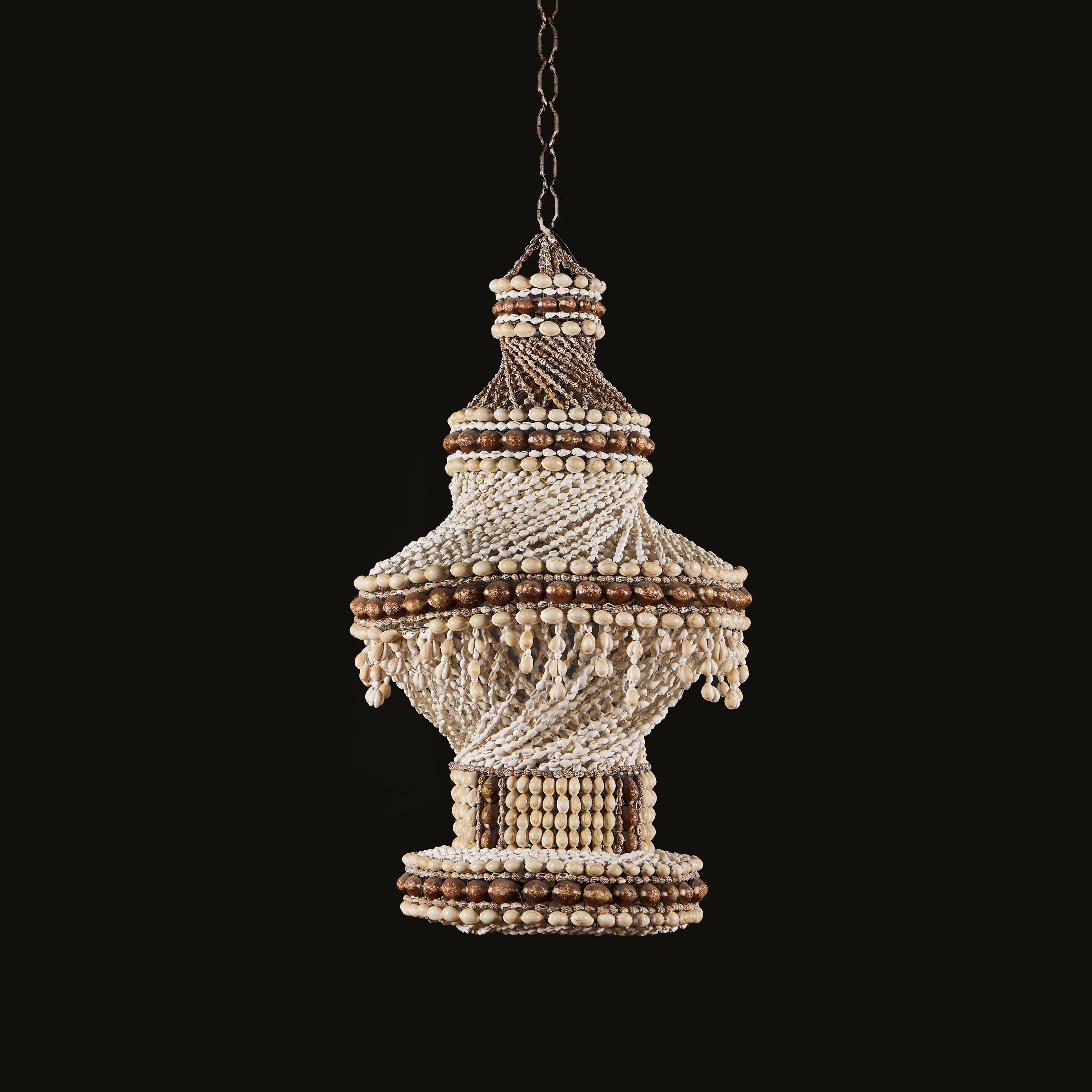 Papua New Guinea, 20th century.

An unusual twentieth century cowrie shell hanging light, with four tiers, and twisting shell beading to the body. 

Currently unwired. Please enquire for wiring services. 