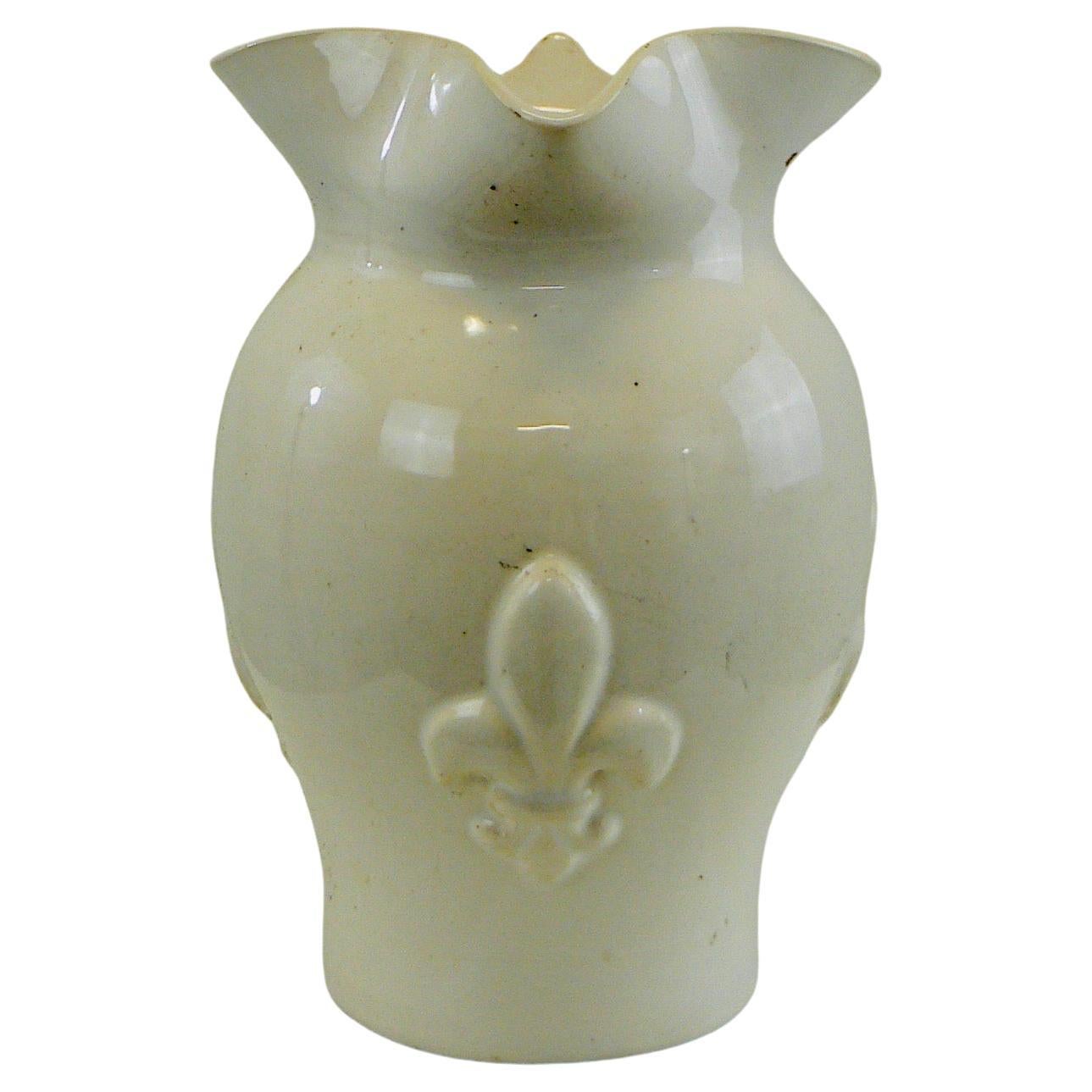 A white glazed ceramic water pitcher with a handle and fleur-de-lys decorations. In perfect condition.






