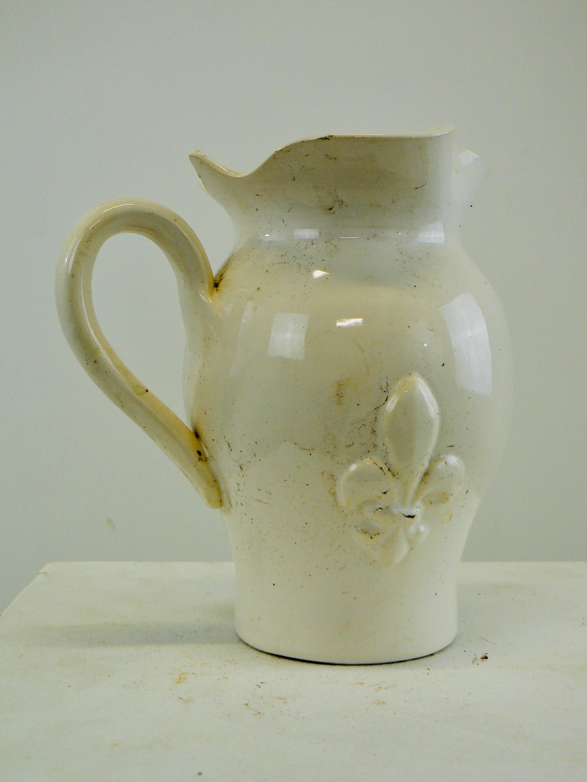 A white glazed ceramic water pitcher with a fleur-de-lys decorations France 