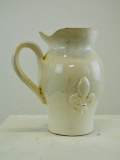 Un pichet à eau en céramique émaillée blanche avec des décorations de fleurs de lys France 