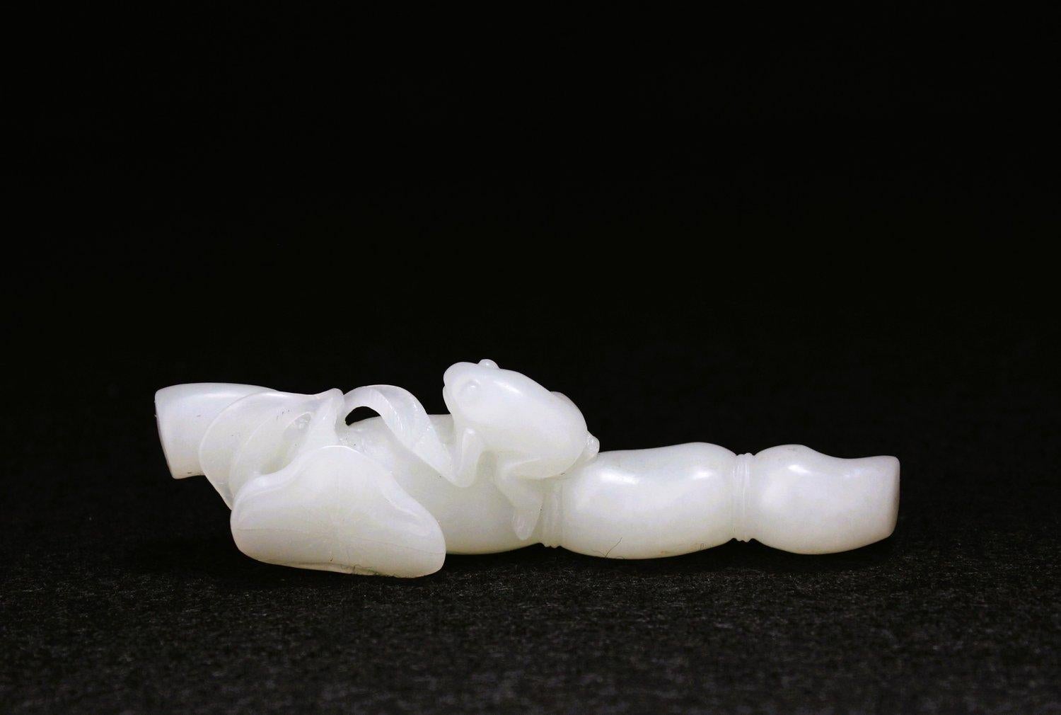 Sculptée comme une racine de lotus élancée à quatre nœuds, avec des feuilles poussant à une extrémité, une grenouille reposant sur le deuxième nœud, cette pièce de jade a un ton blanc uniforme et est bien sculptée et polie.

Ce porte-brosse est