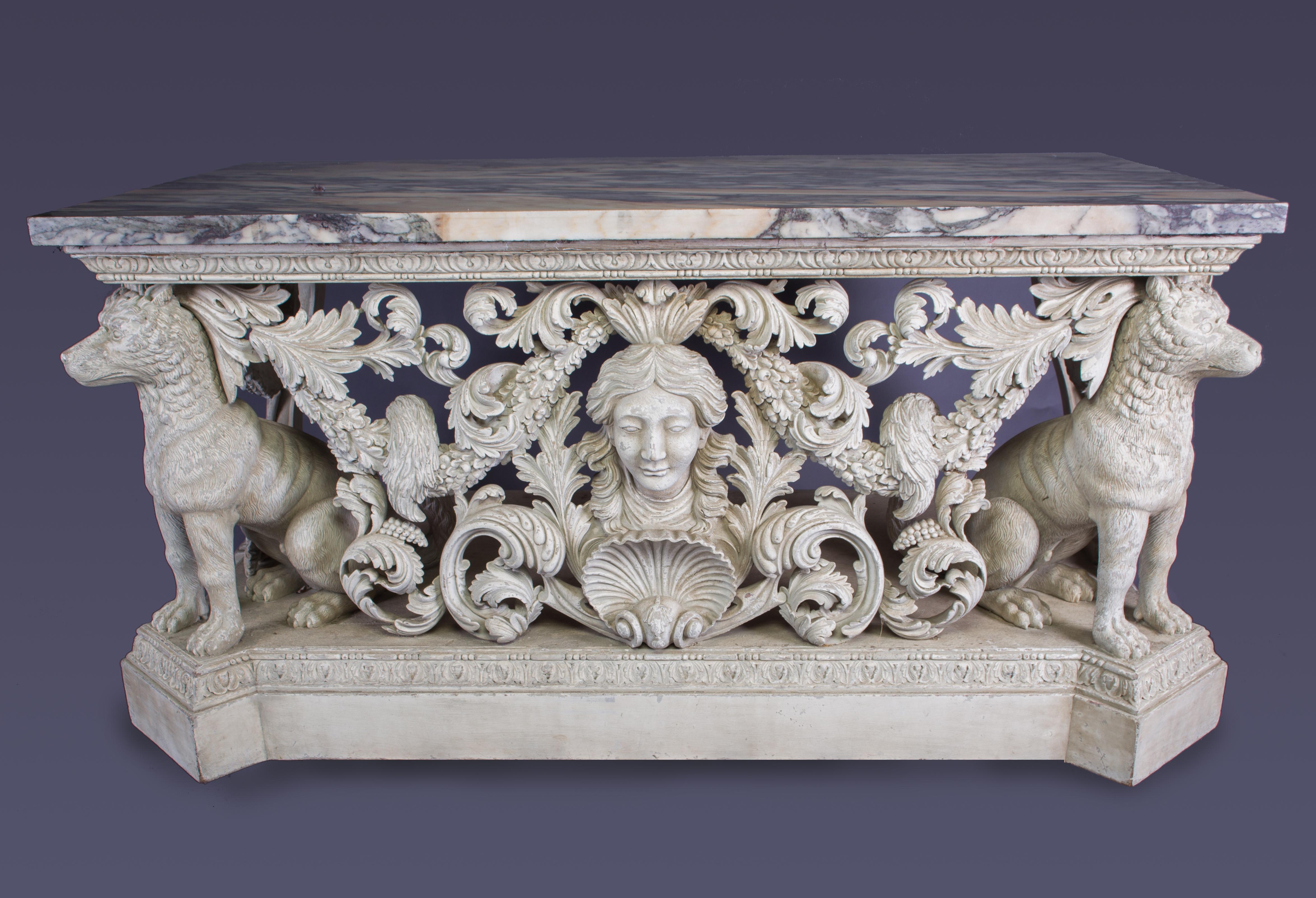 An Impressive carved painted console tables after the design by William Kent
The rectangular Breccia marble top above well carved seated dog supports, with a central female mask above a scallop shell, surrounded by carved acanthus.

English, 20th