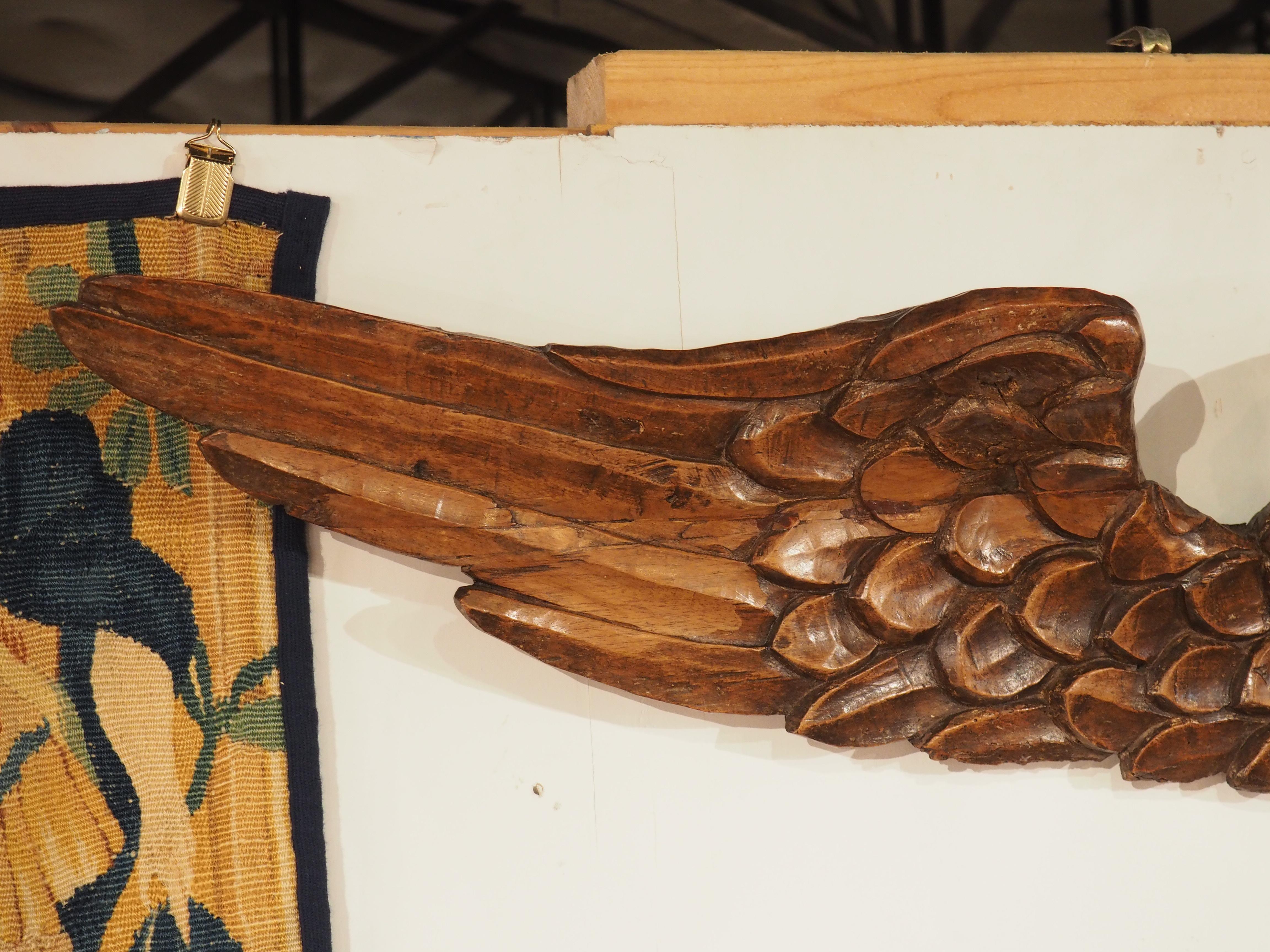 Mit einer Breite von über einem Meter hat diese geflügelte Engelsfigur eine beeindruckende Spannweite. Die um 1600 in Frankreich aus Nussbaumholz handgeschnitzte Skulptur zeigt das unschuldige Gesicht eines Engels mit seitlich ausgebreiteten