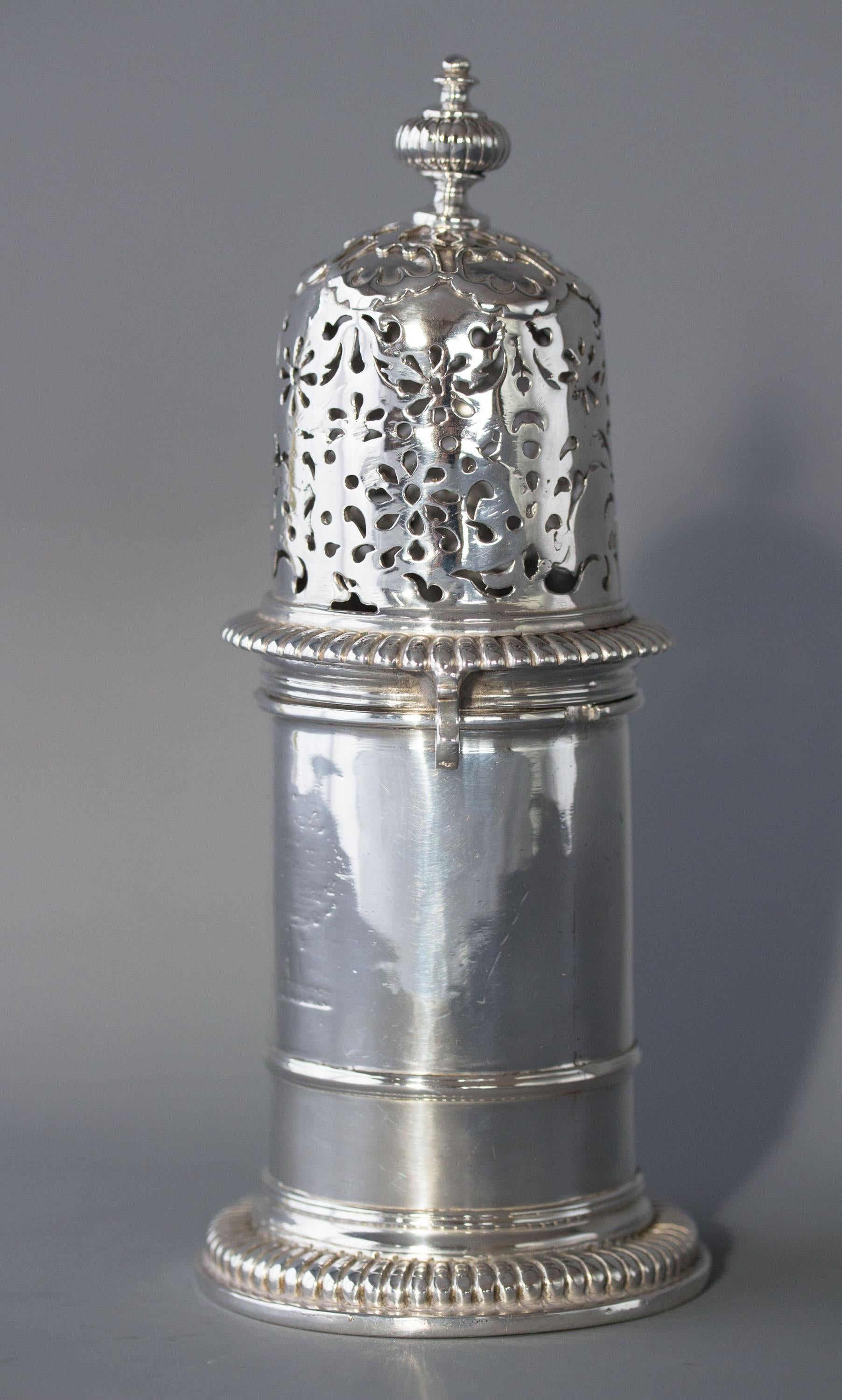 A very rare William III britannia silver lighthouse caster, London 1698. Britannia Standard, with a turned and fluted finial to the domed, pierced cover engraved with scrolls and flowers with bayonet fixing mounts. The main body of the caster is