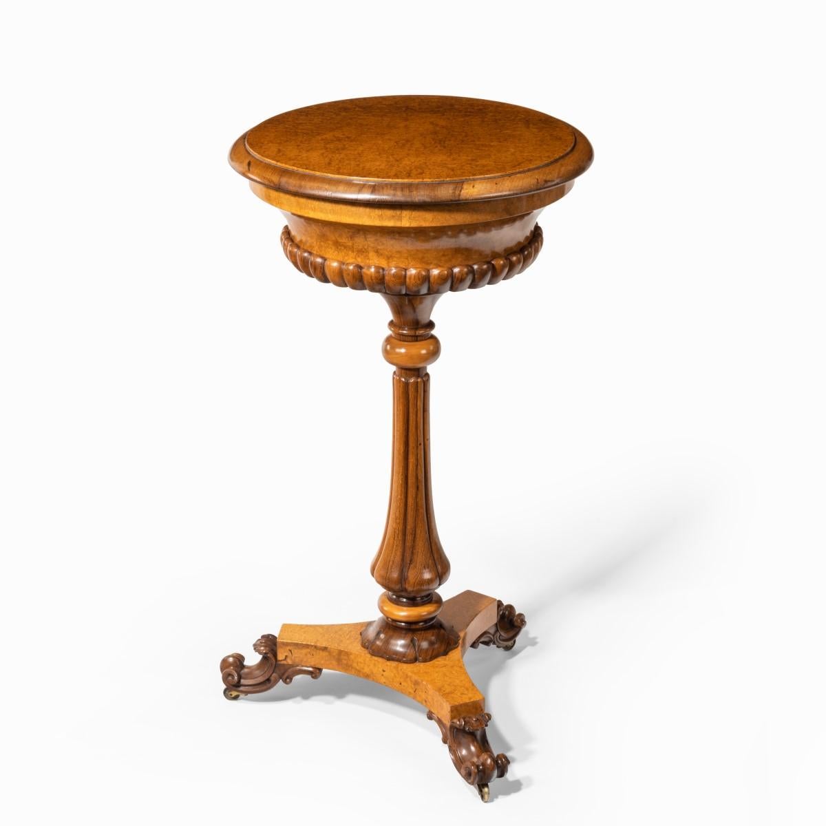 A William IV amboyna and rosewood table / jardiniere, in two sections with a fitted circular cover above a sloping bowl enclosing a replaced brass lining, bold gadrooning to the underside, all raised on a single turned, tapering and lobed support,
