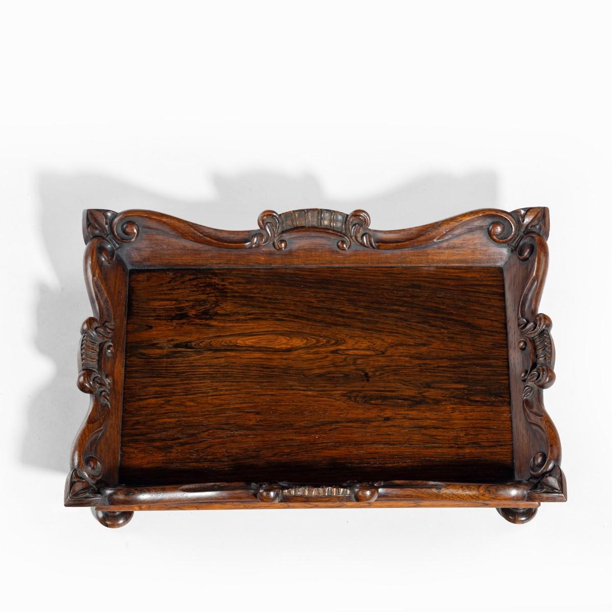 A William IV rosewood desk tidy attributed to Gillows, of rectangular form with everted, bracket sides carved with S-scrolls and pointed trefoil corners, raised on four turned feet.  English, circa 1830.

