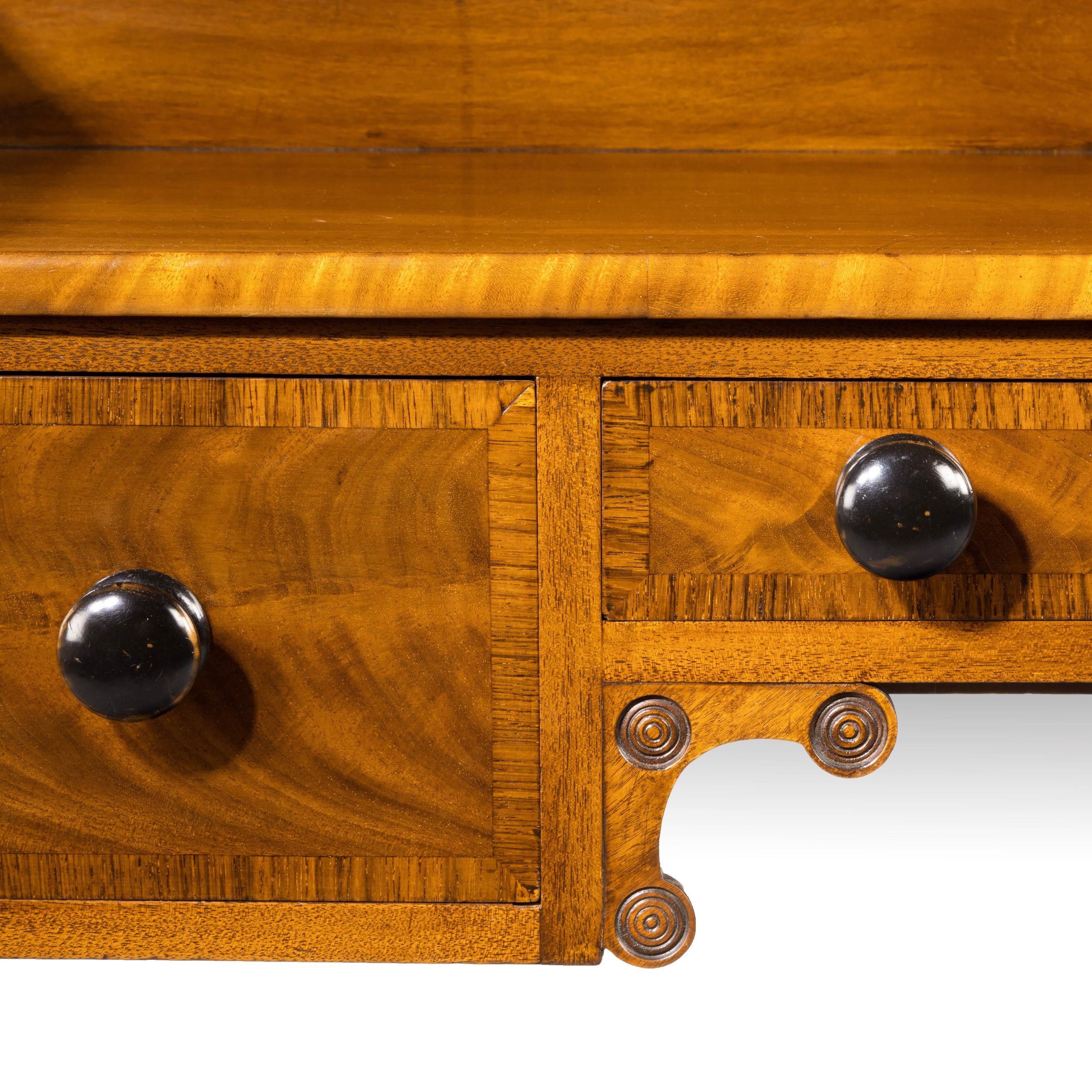 A William IV side or serving table very much in the manner of Gillows of Lancaster. The top edge entirely crossbanded as are all three drawers. Retaining the original period turned knobs Very well-turned and complex circular uprights. The backward
