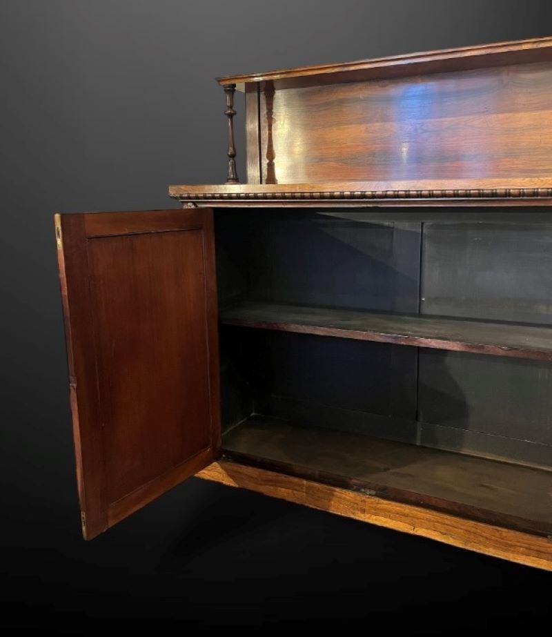 Un chiffonnier en bois de rose riche et distinctif avec une seule étagère à l'arrière sur des supports tournés.

Le meuble repose sur un socle et présente de jolis détails sculptés de part et d'autre des portes, qui sont à la fois doublées et