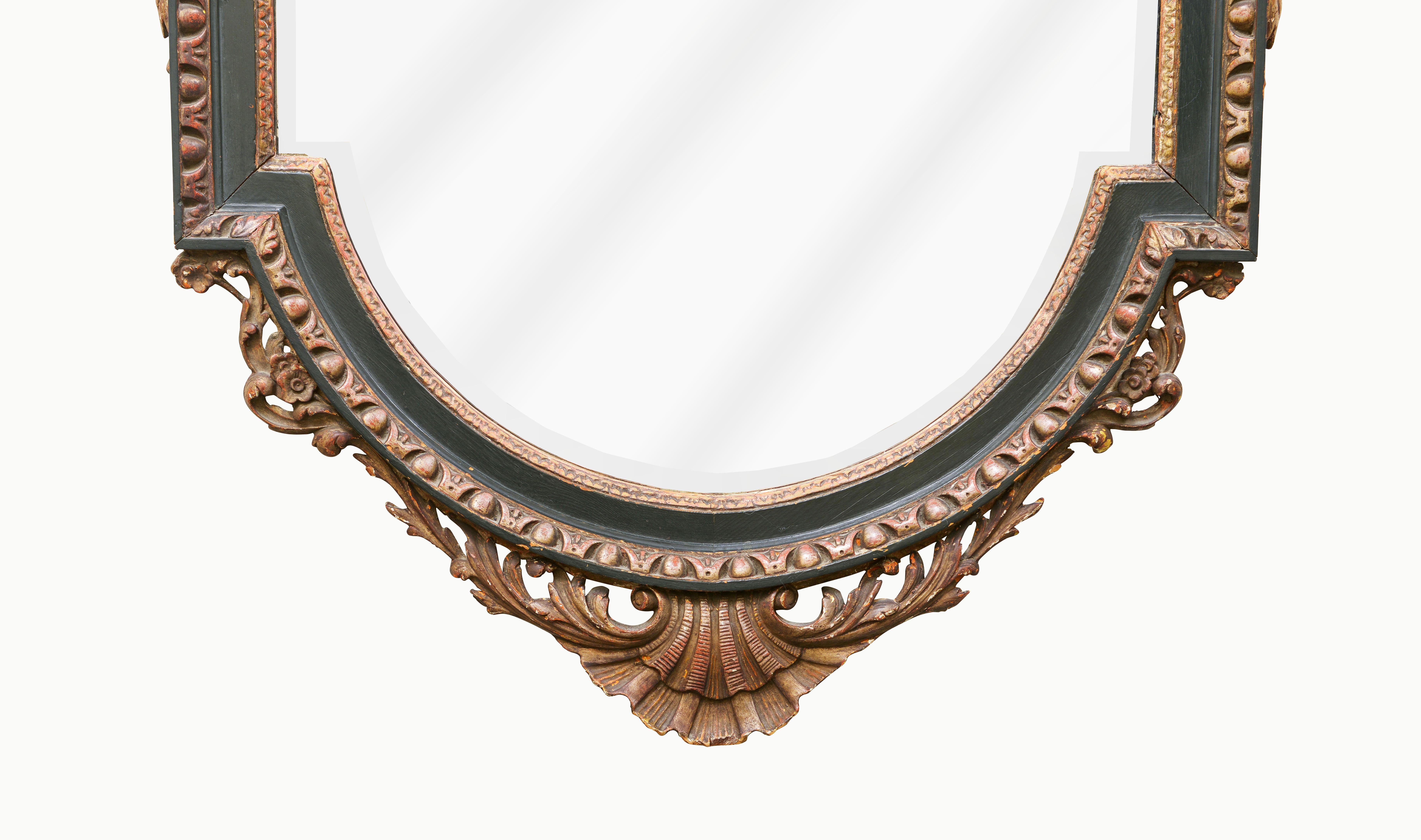 Richly carved and substantial quality. The beveled mirror plate surmounted by a broken arch pediment, enriched with egg-and-dart ornament and centered by a scallop shell issuing floral garlands above an acanthus clasp, above a stiff-leaf carved