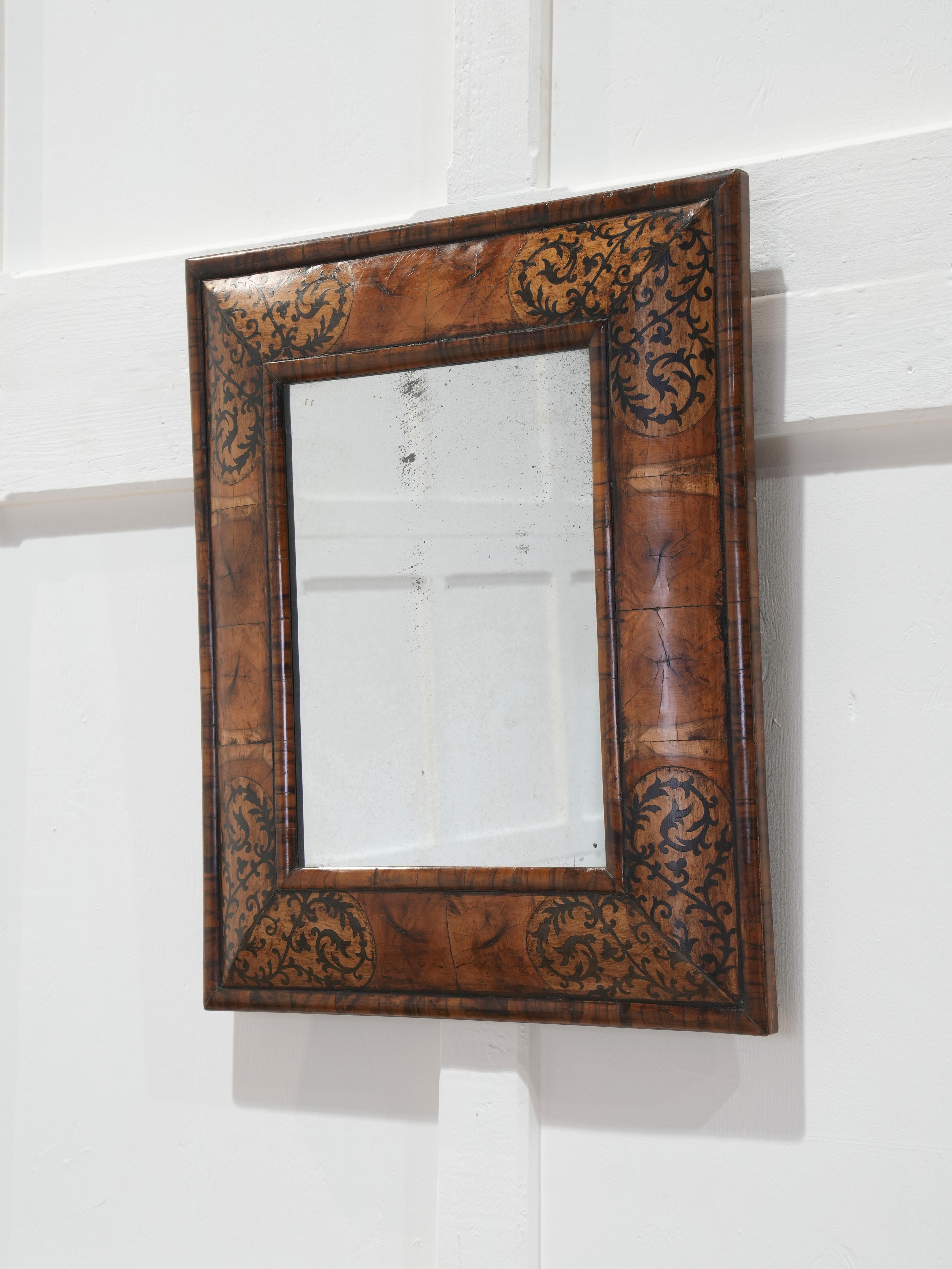The frame veneered with individually end cut yew block with walnut borders and ebony inlay, lightly foxed mirror plate,

circa 1690-1700.