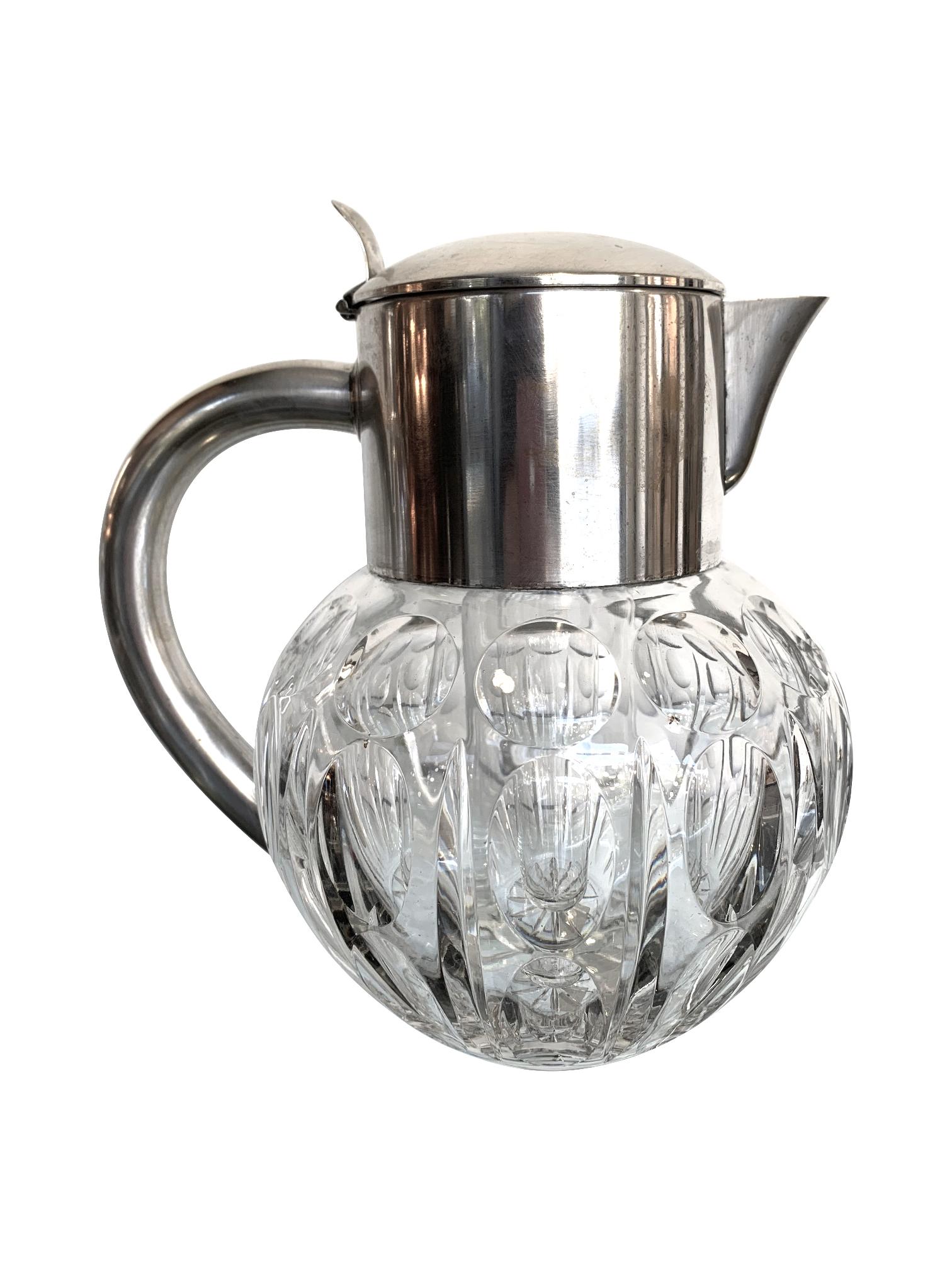 A WMF silver plated crystal lemonade / cocktail jug engraved with circle motifs. Mounted with a hinged silver plated lid and handle that opens to reveal the central glass ice compartment. Stamped on the back 