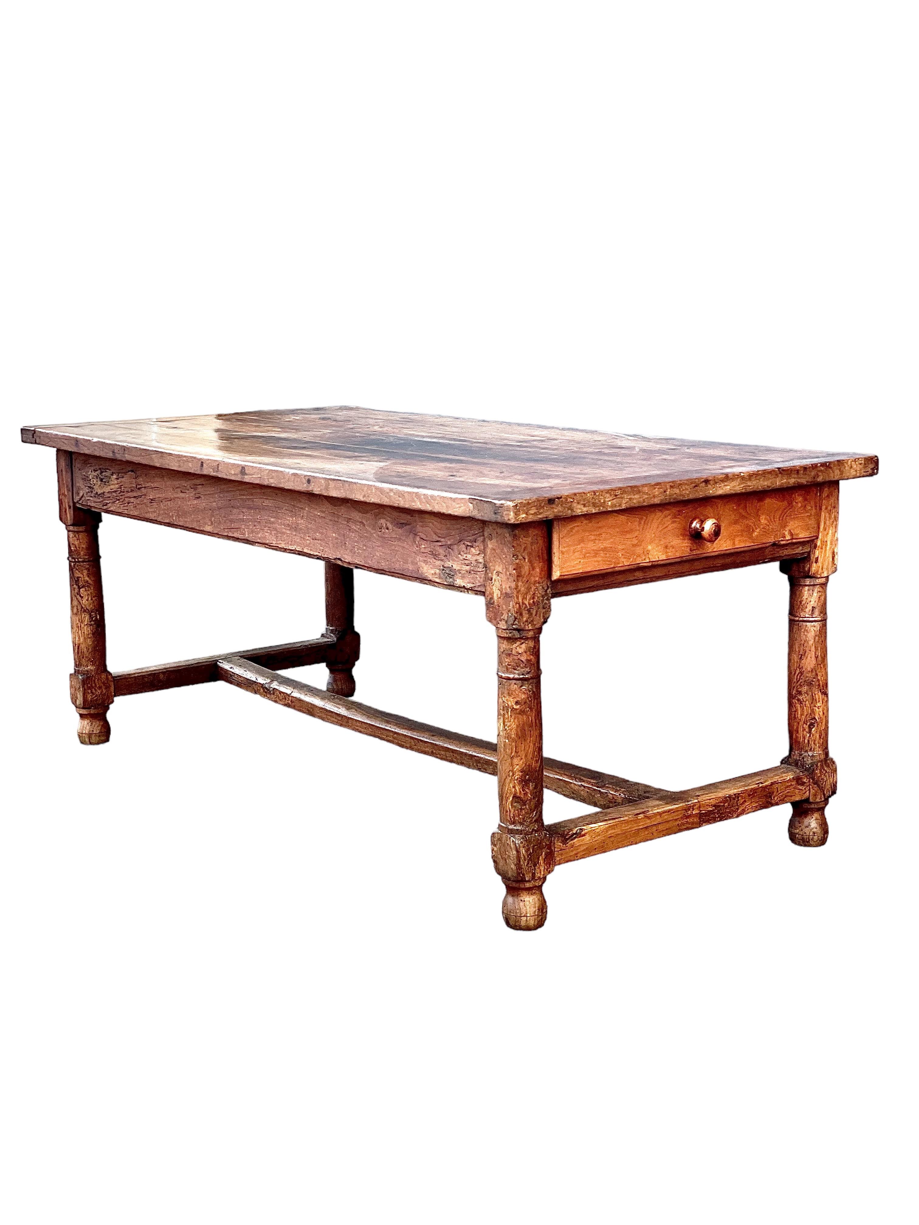 A wonderful French farmhouse kitchen table, dating from the 18th century and full of character. This sturdy, rectangular table has its original, planked top and cleated ends, and stands on thick, baluster-turned legs, joined by an 'H' stretcher,