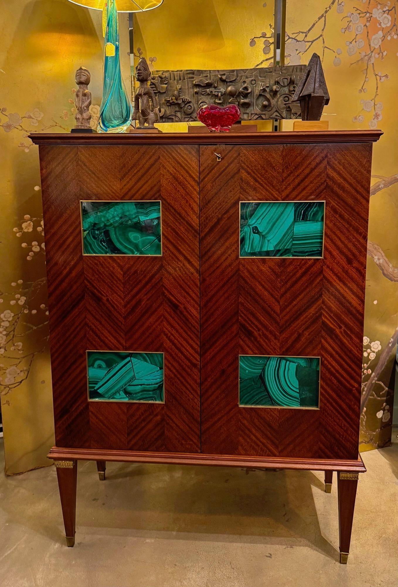 Un meraviglioso mobile bar degli anni '50 di Paolo Buffa con una splendida impiallacciatura in mogano a osso di aringa su entrambe le porte anteriori e sui lati. Ogni porta ha due pannelli in finta malachite con bordo in ottone. C'è la chiave e la