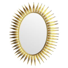 Magnifique miroir à cils en métal doré des années 1950, de forme ovale, à décor de soleil espagnol.