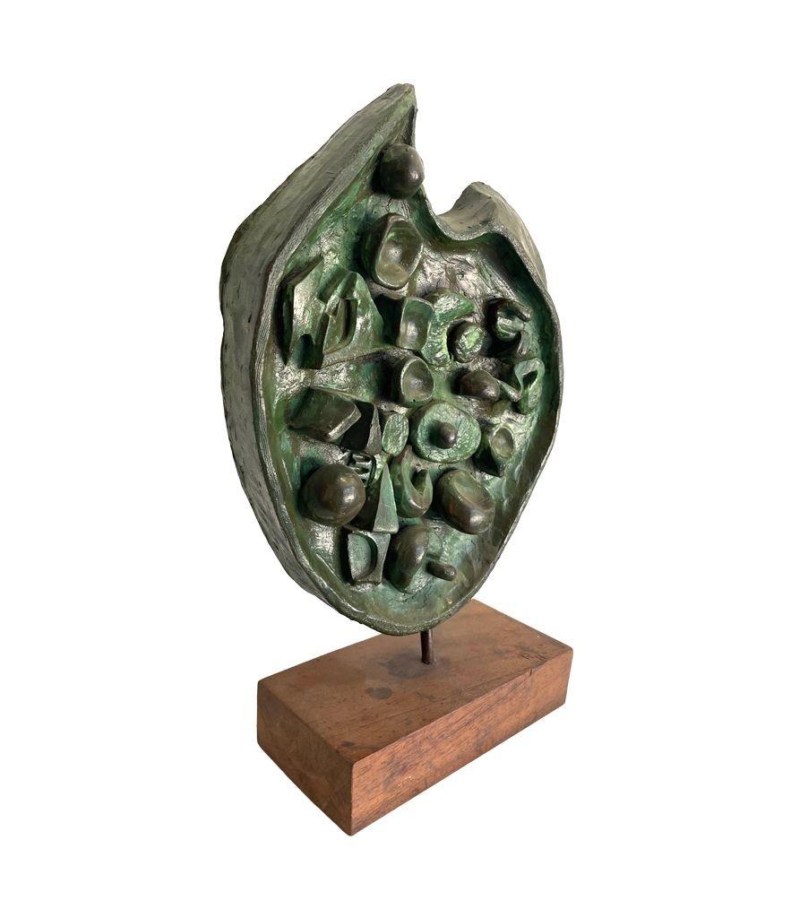 A wonderful 1950s abstract fibreglass sculpture by Ron Hitchins in Verdigris finish, mounted on wooden stand with carved initials 