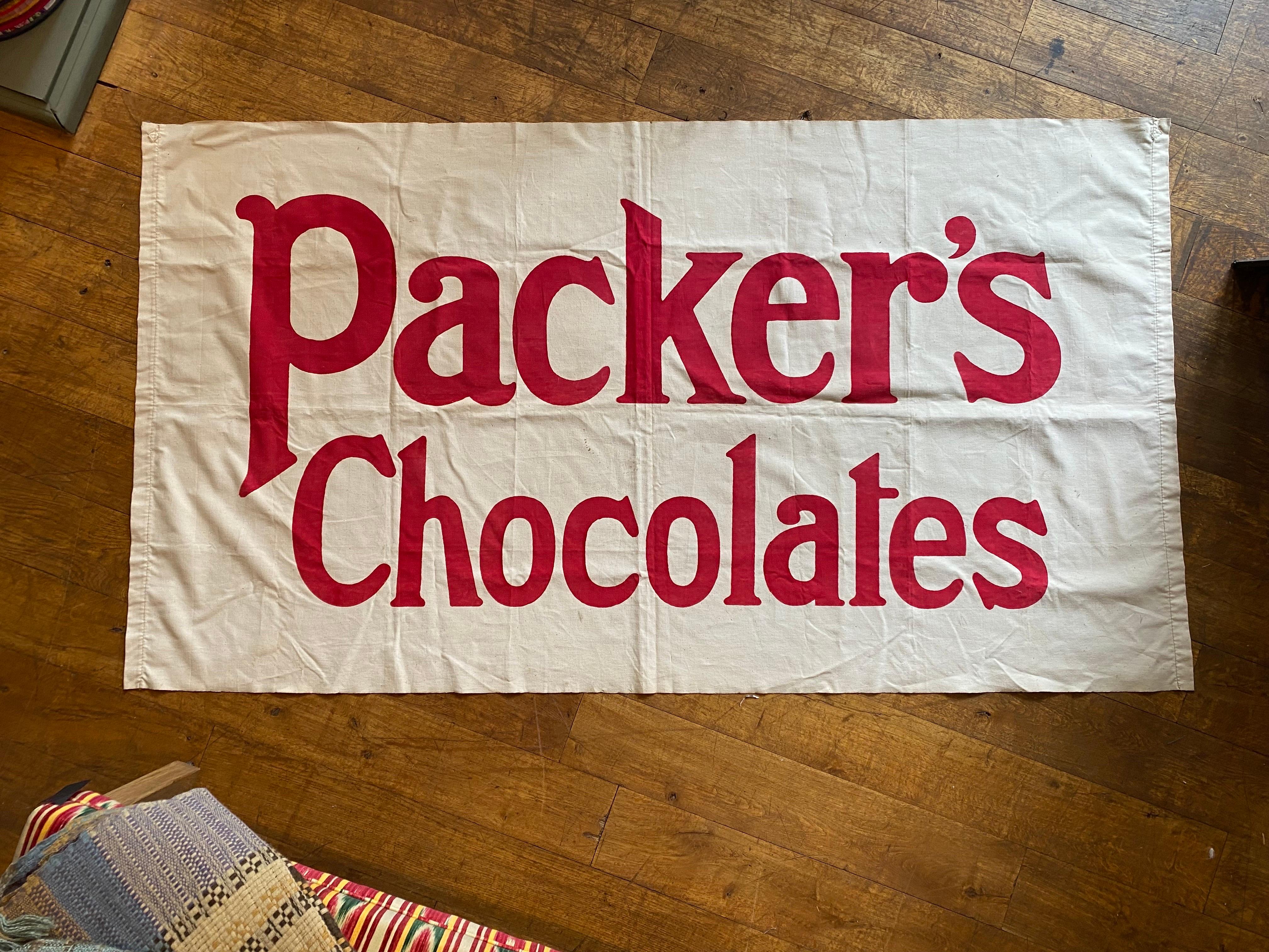 A beautiful and vibrant advertising banner for Packer’s Chocolates circa 1940. The printed red lettering on the white cotton backing is still very strong and the whole piece is in excellent condition with the original hanging loops to the rear.
