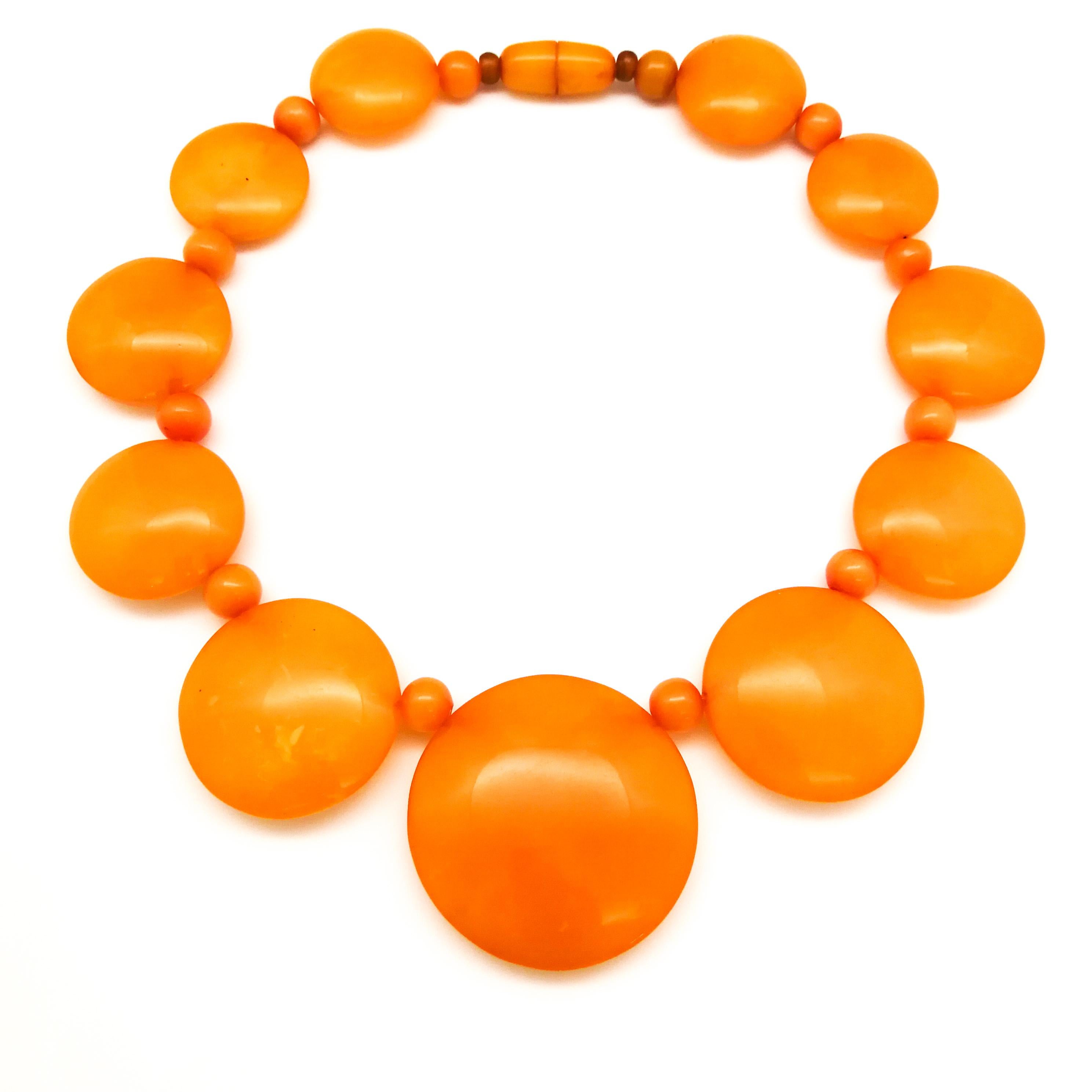 A wonderful bright orange Bakelite three piece parure/set, consisting of a graduated 'disc' necklace, a simple, solid bangle and a large and stylish ring, all in excellent condition, having travelled through time from the 1930s, remarkably