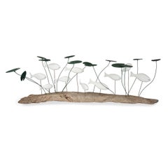 A wood and metal sculpture of a shoal of fish amongst lily pads by Martin Scorey
