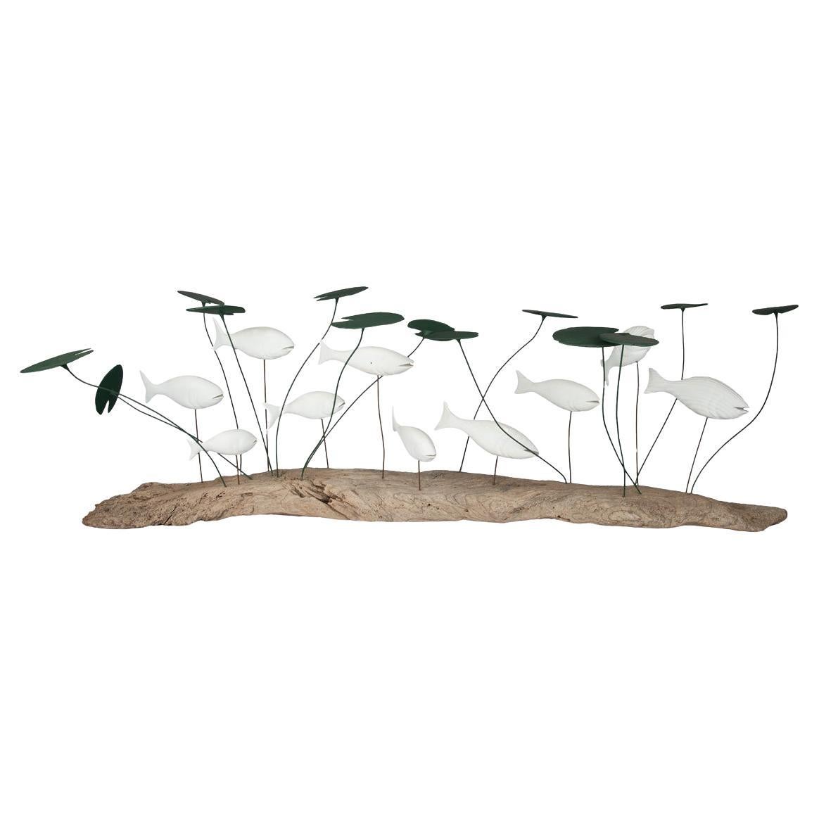 A wood and metal sculpture of a shoal of fish amongst lily pads by Martin Scorey