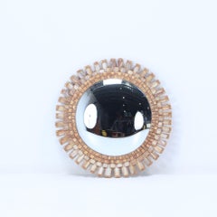 A wood and resin convex mirror having a geometric border of ivory colored glass