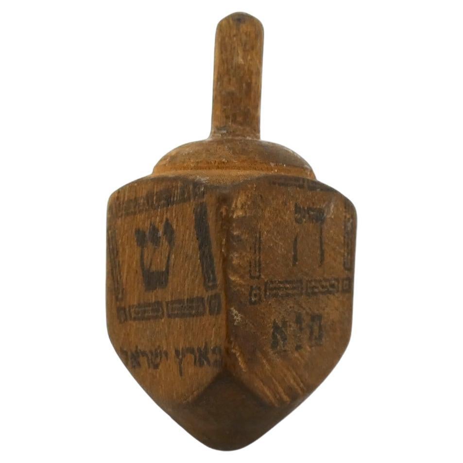 A Classic Wooden Dreidel made in Jerusalem between 1920-1930.

This dreidel is hand-carved and made in a classic design with four flat sides. At the top is a carved dome with a protruding cylindrical handle and each side is stamped with a Hebrew