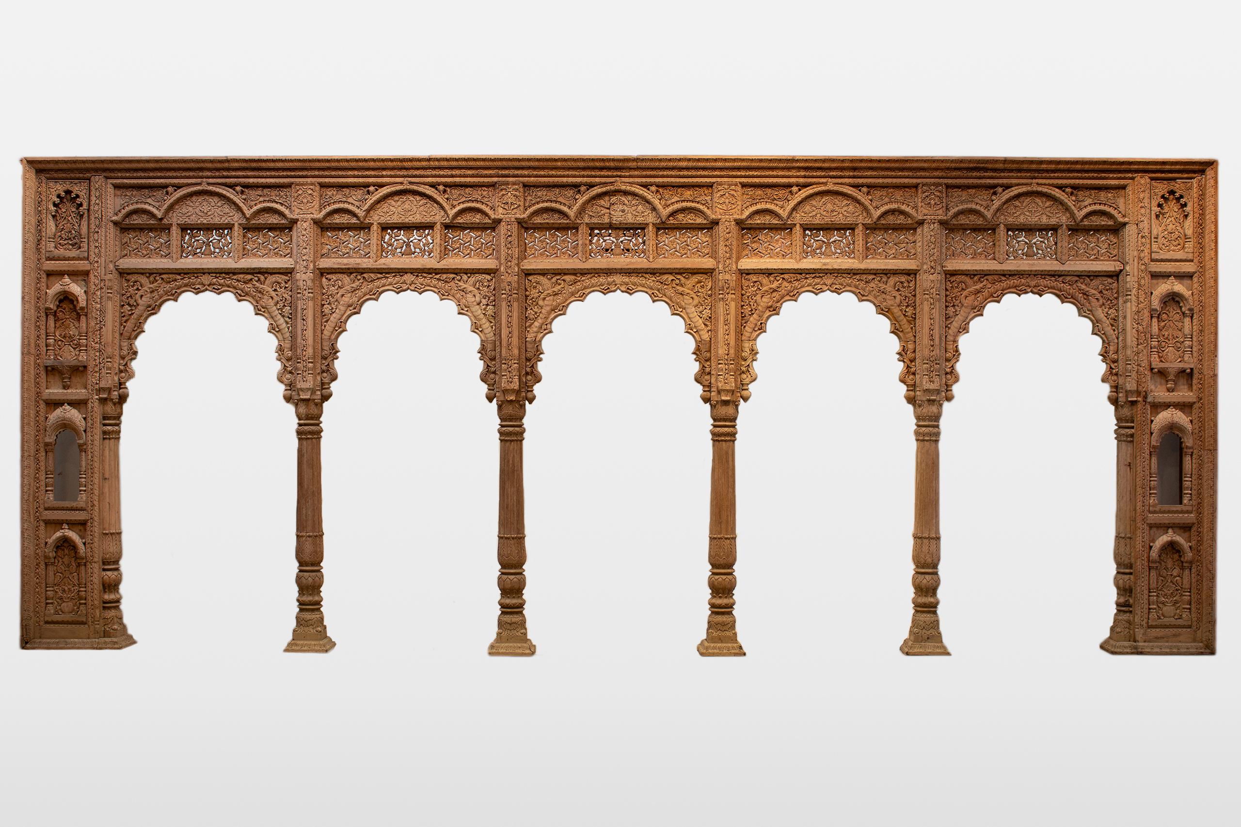 Esta exquisita columnata indo-sarracena, hecha a mano en el siglo XXI con madera de sheesham, capta la belleza intemporal de la arquitectura tradicional india. Actualmente en su estado natural sin pintar, la arcada exhibe una talla intrincada y una