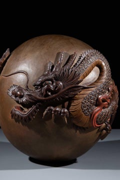 A wooden sculpture in the form of a sphere with a dragon carved in the round
