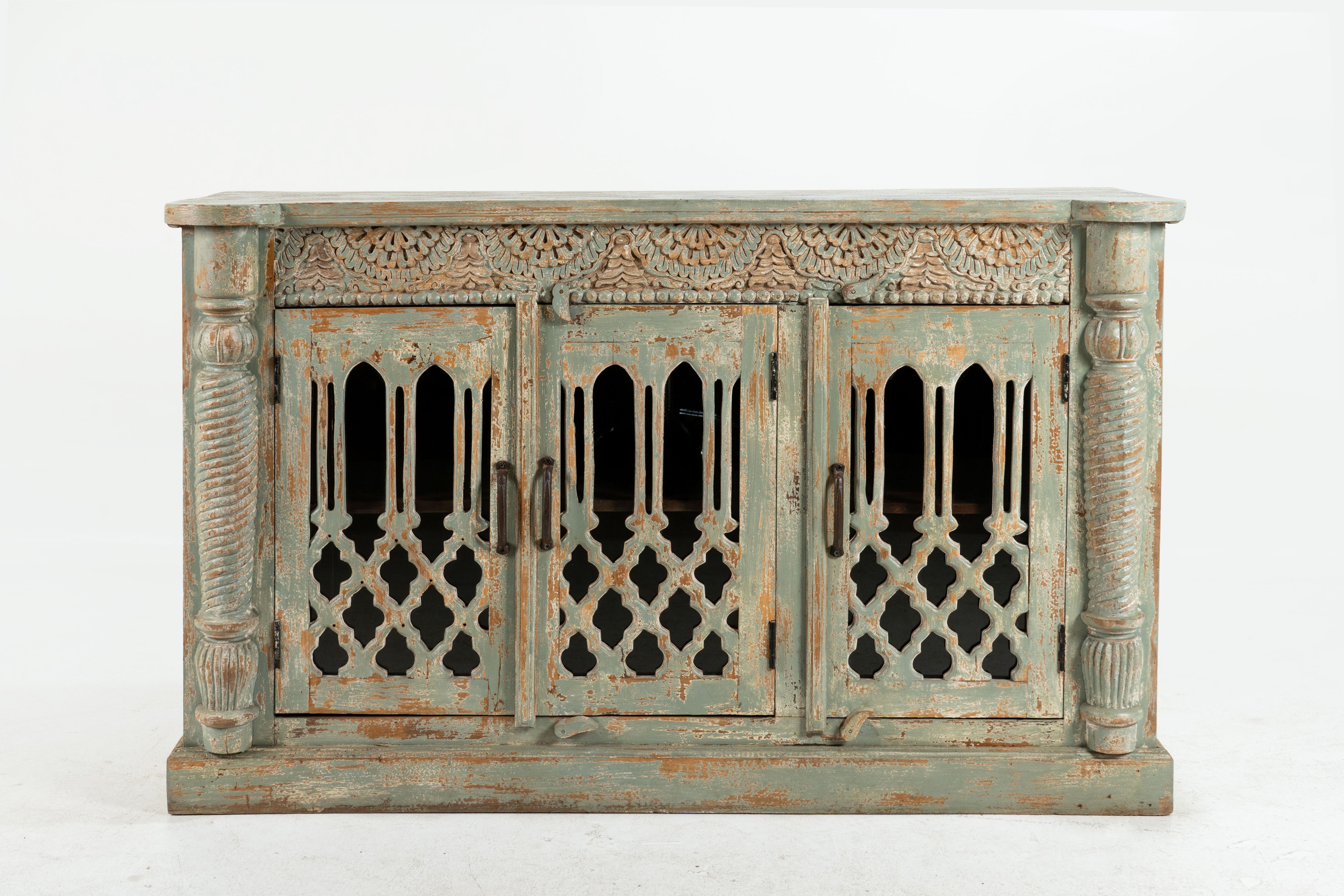 Questa squisita credenza indo-saracena, assemblata nel XXI secolo, utilizza legno di mango sostenibile per garantire durata e responsabilità ecologica. Dipinto in un rilassante verde acqua chiaro, per lo più sbiadito, emana un'estetica fresca ed