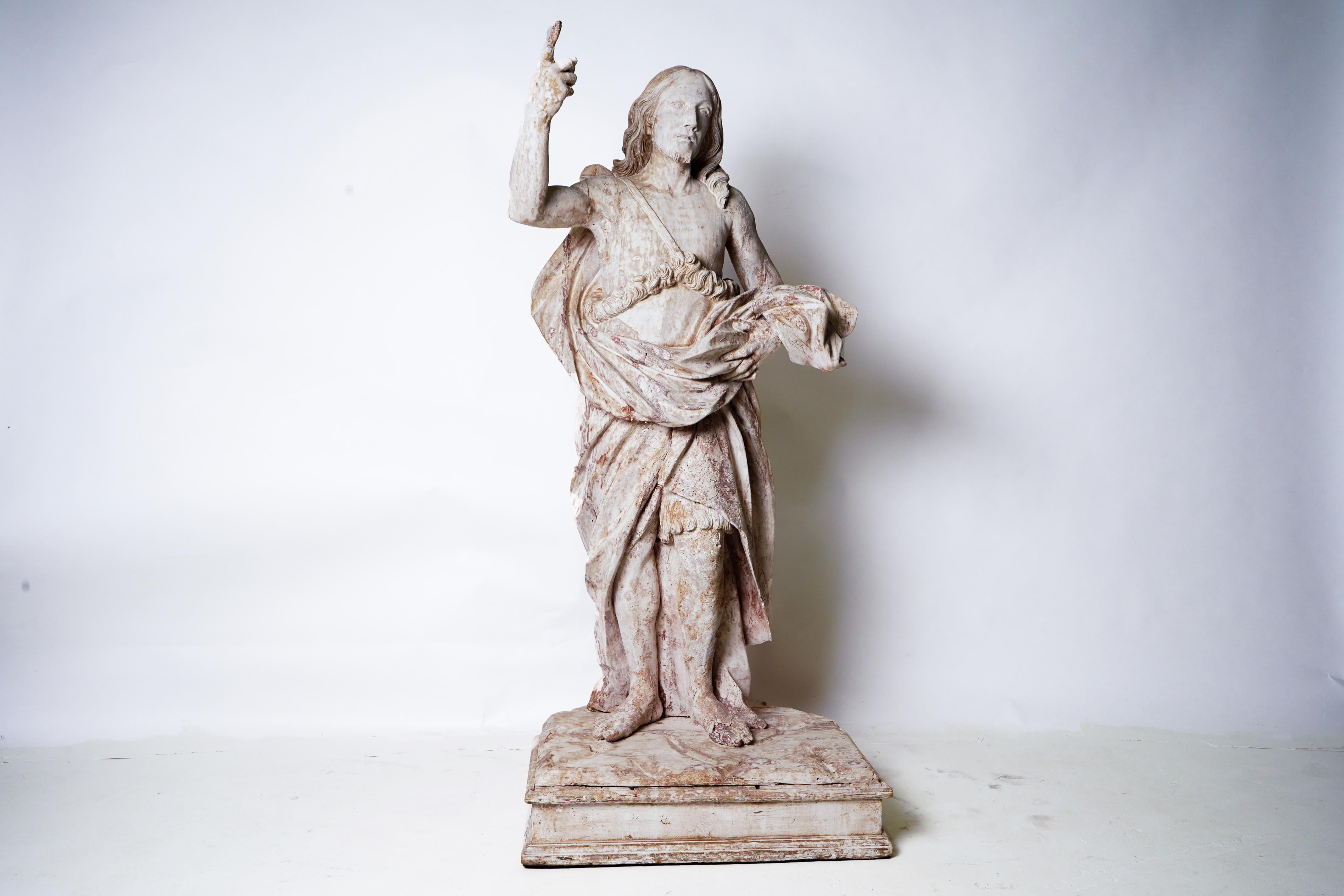 This exceptionally life-like antique sculpture is carved from linden wood and once decorated a French church or cathedral. The figure stands authoritatively, with right arm raised and index finger extended toward heaven. It probably stood on a base