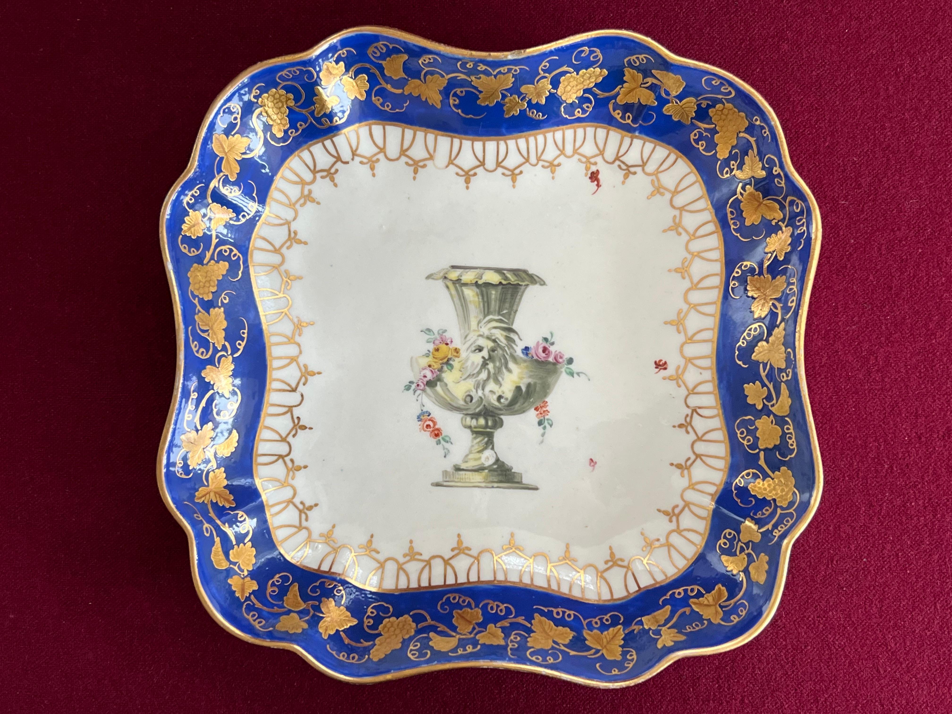 A fine Worcester porcelain square dish circa 1770. Finely decorated in the London atelier of James Giles. Decorated with an overglaze royal blue border and tooled gilding. The central cavetto decorated in typical Giles style with a classical urn