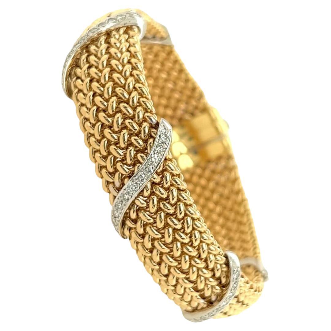 Ein Armband aus 14 Karat Gelb- und Weißgold mit Diamanten.  Das flexible Gelbgoldgeflecht ist mit fünf schlangenförmigen Diagonalen aus Weißgold und einer senkrechten Schließe versehen, die mit dreiundsechzig (63) runden Diamanten im Brillantschliff