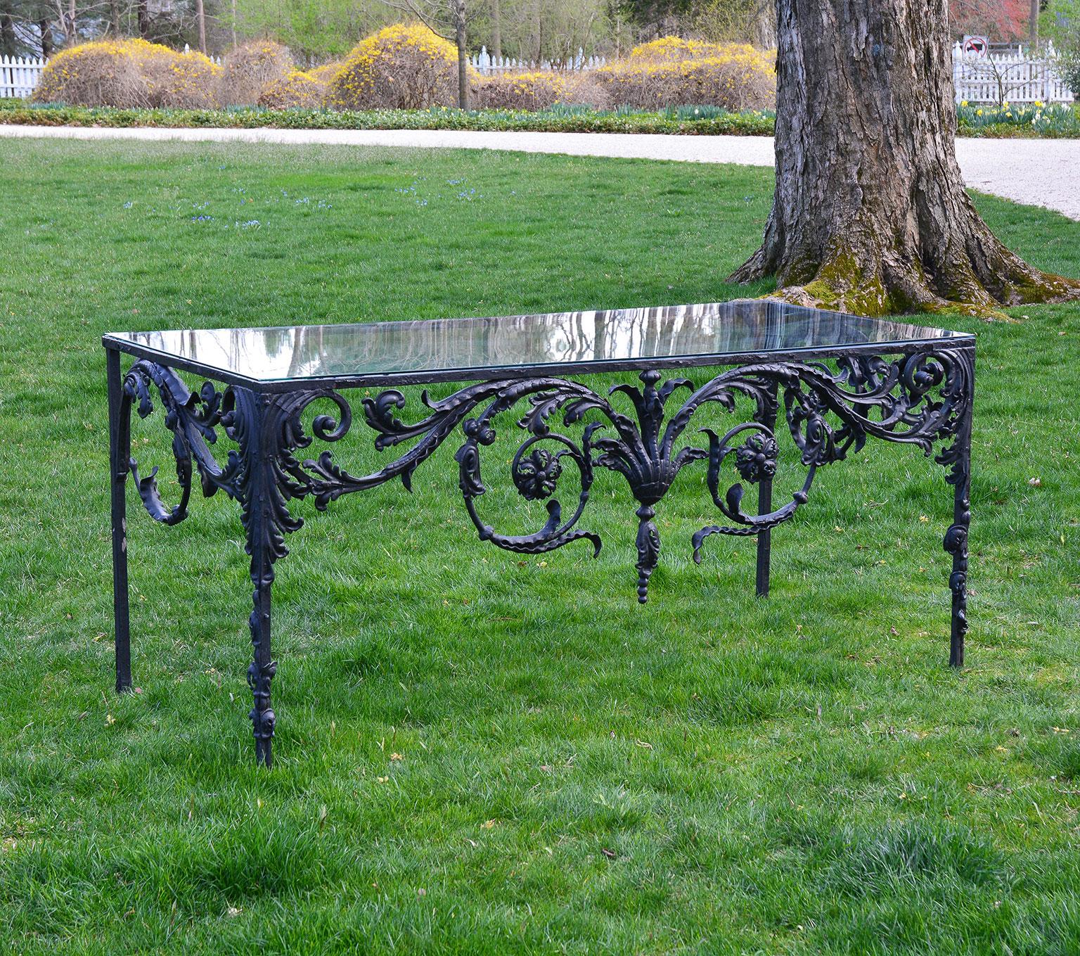 A cast and wrought iron console table with elaborate scrollwork and foliate motifs, with glass top. Provenance: Estate of Peggy & David Rockefeller.
 
